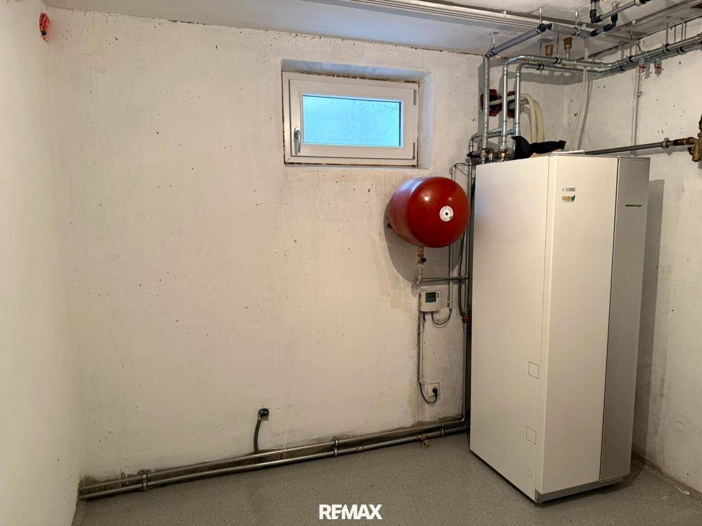 Heizungsraum im Keller mit moderner Heizungsanlage und Warmwasserspeicher.