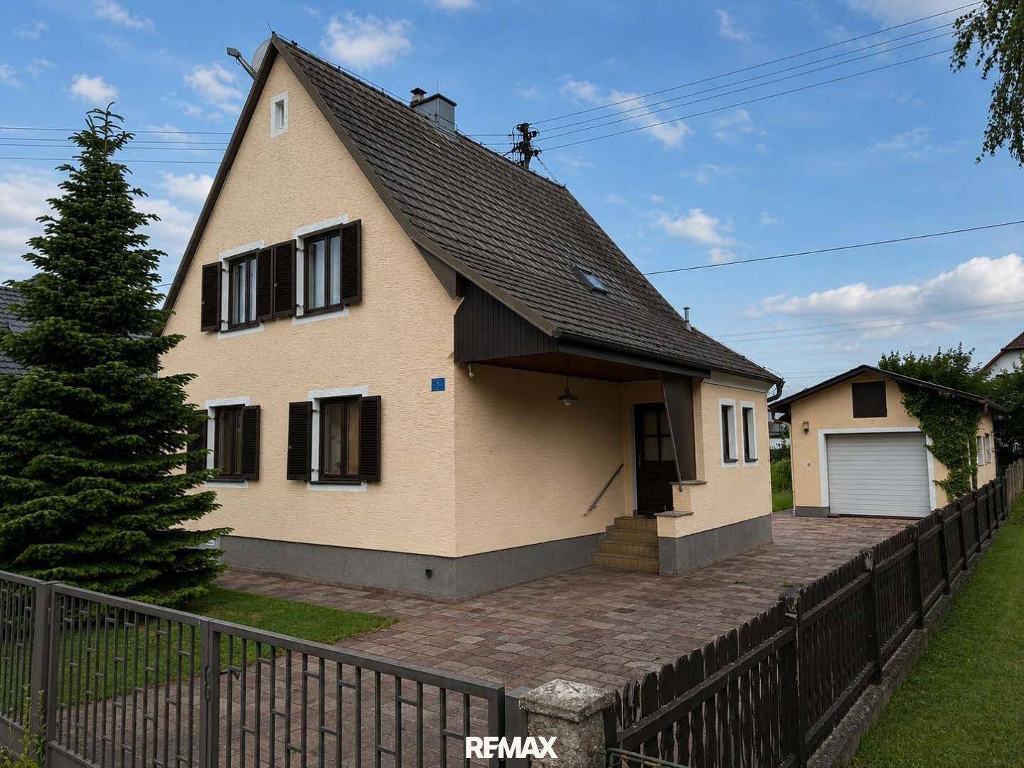 Ansicht des Einfamilienhauses von vorne mit gepflasterter Auffahrt und separater Garage.