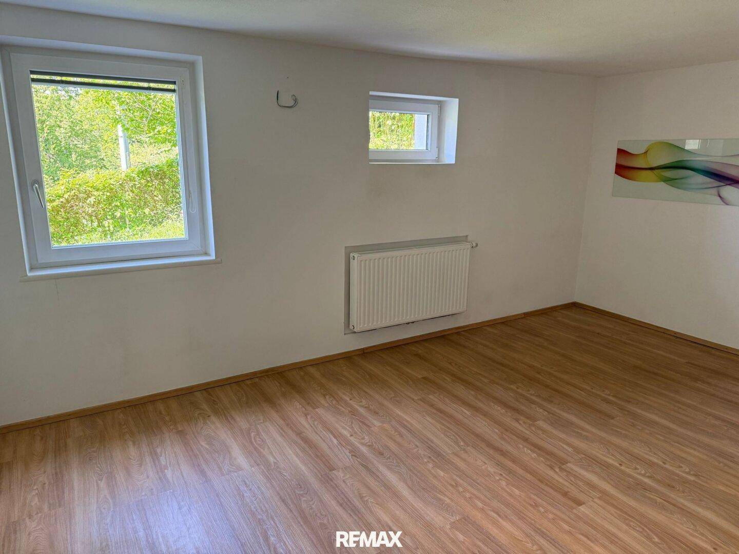 Heller Raum mit Laminatboden und zwei Fenstern, bietet vielseitige Nutzungsmöglichkeiten.