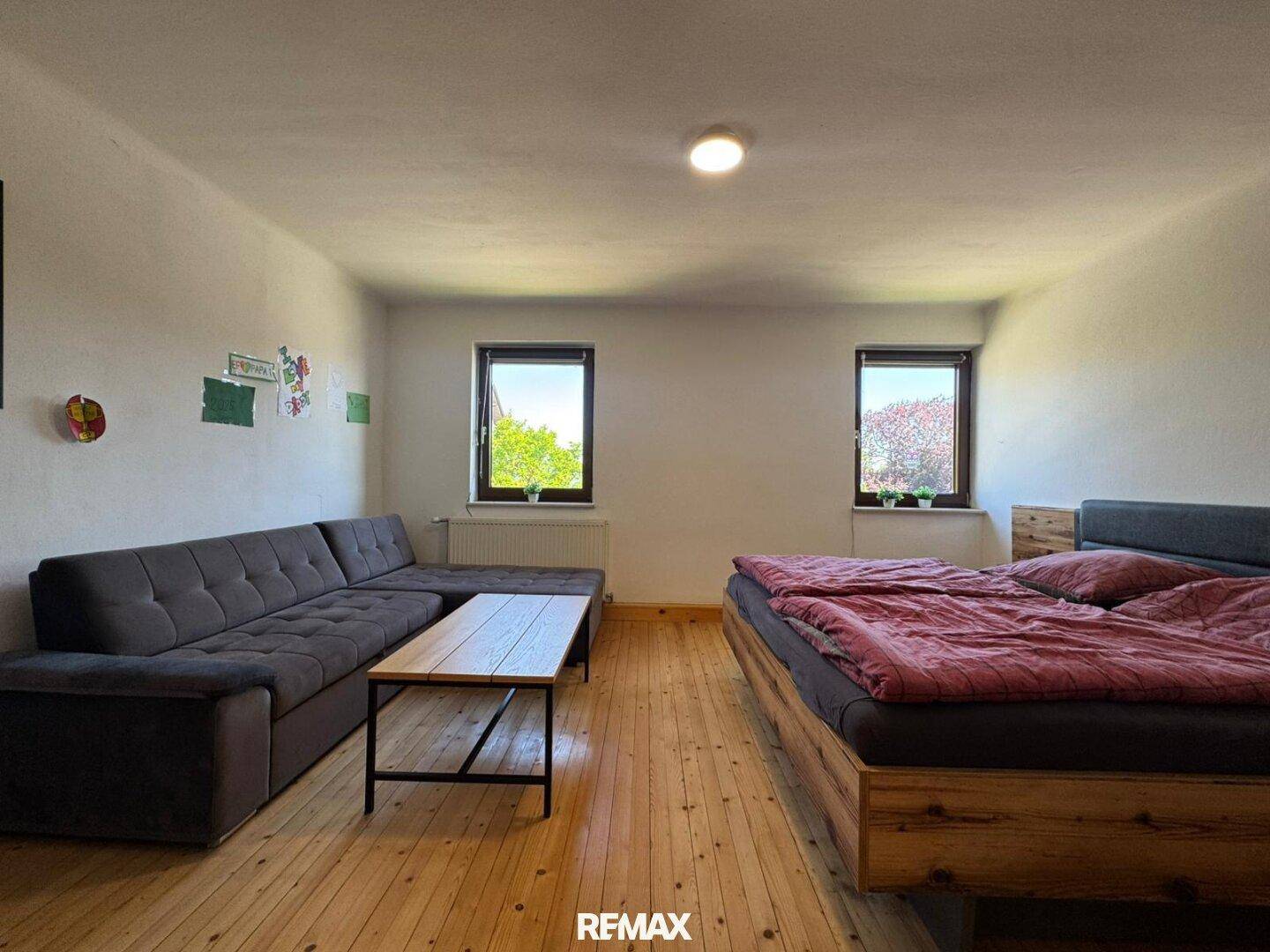 Helles Schlafzimmer mit Holzboden, großem Bett und Sofa, bietet viel Platz.