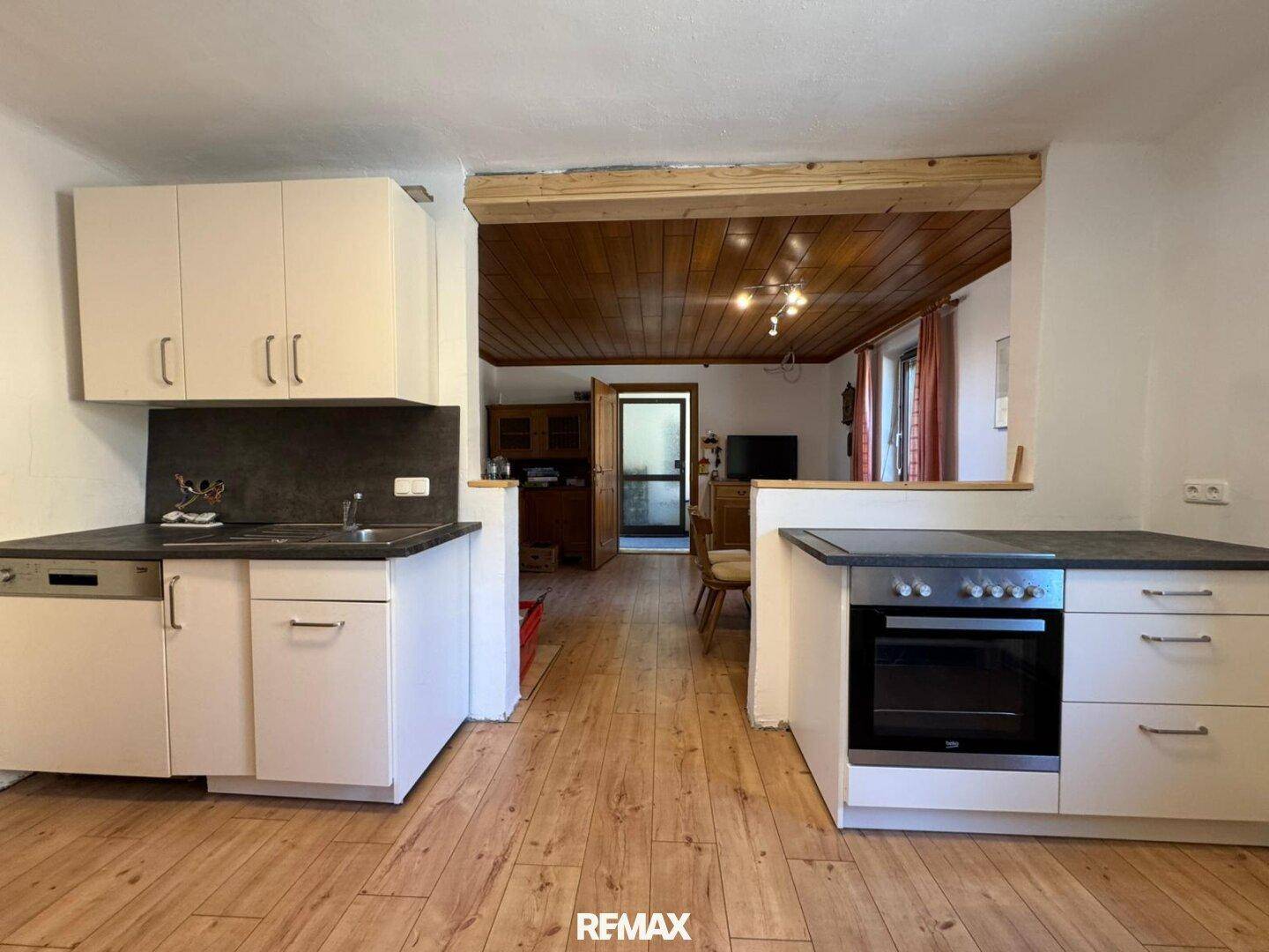 Funktionale Küche mit weißen Schränken und Holzboden, offen zum Essbereich.