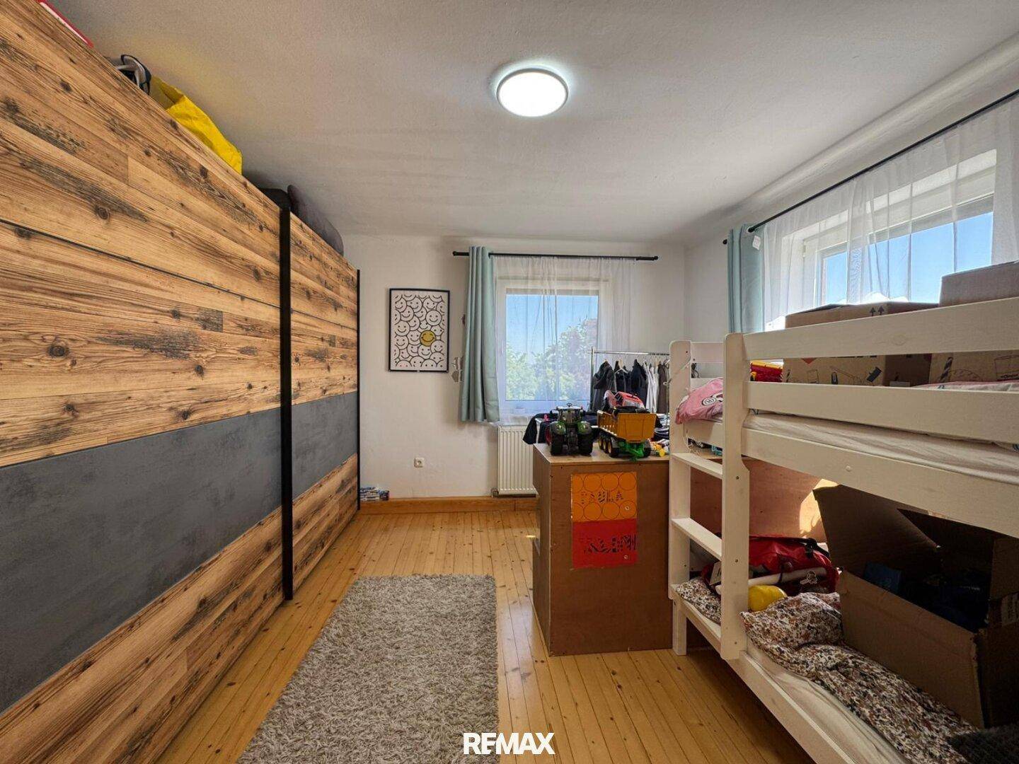 Kinderzimmer mit Etagenbett, Holzboden und großem Kleiderschrank.