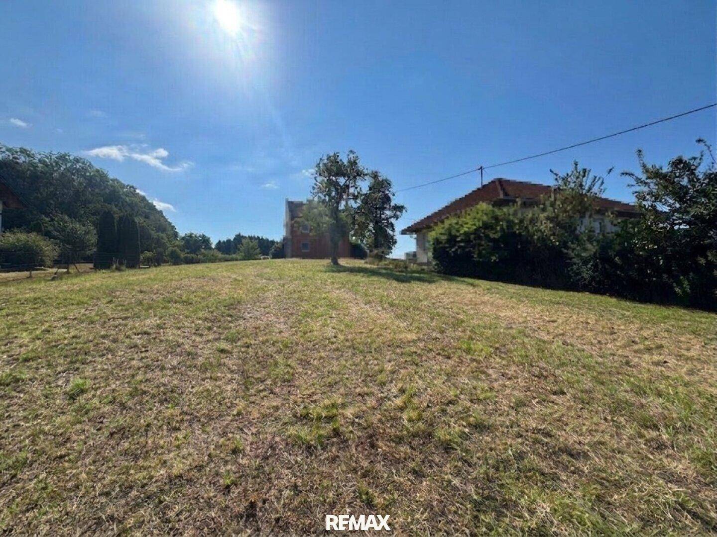 Hügeliges Grundstück mit weitem Blick unter strahlend blauem Himmel und Sonnenschein über die Landschaft.
