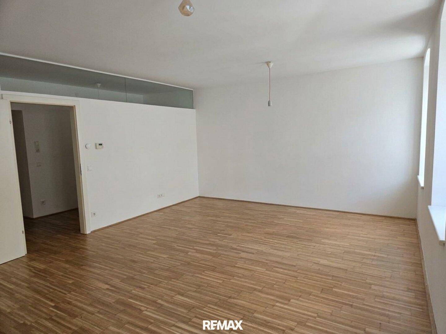 Helles, leeres Zimmer mit Parkettboden und weißen Wänden, bereit zur individuellen Gestaltung.
