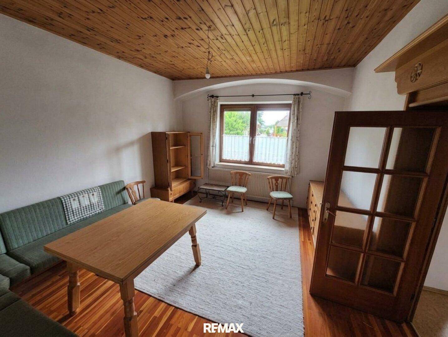 Wohnzimmer mit Holzboden, Holzdecke und traditionellen Möbeln.