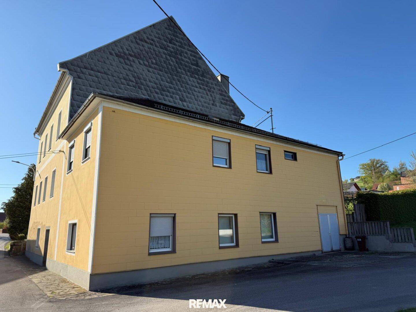 Seitenansicht des Gebäudes mit gelber Fassade und Schieferdach.