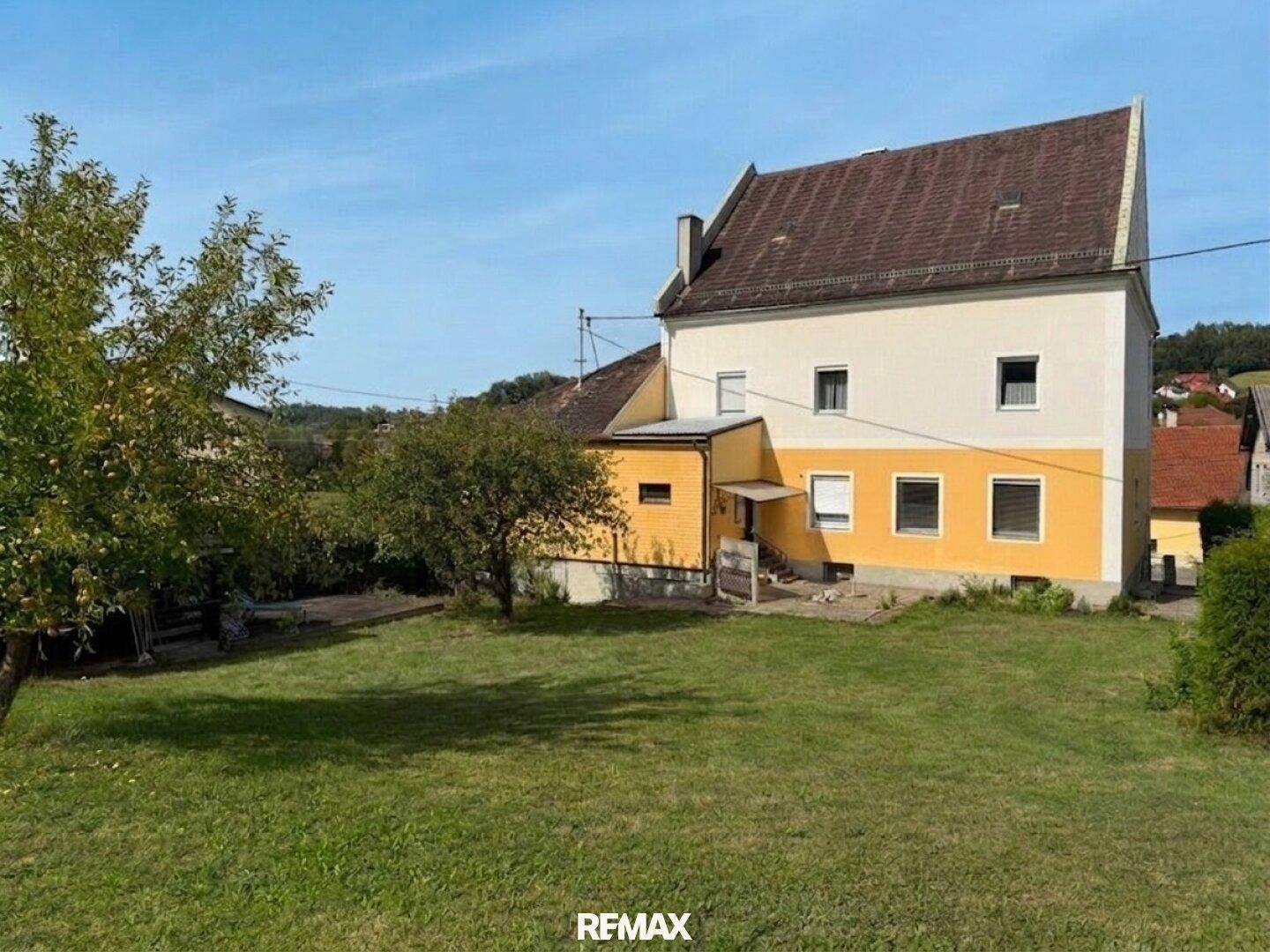 Rückansicht des Gebäudes mit großem, gepflegtem Garten und Obstbäumen.