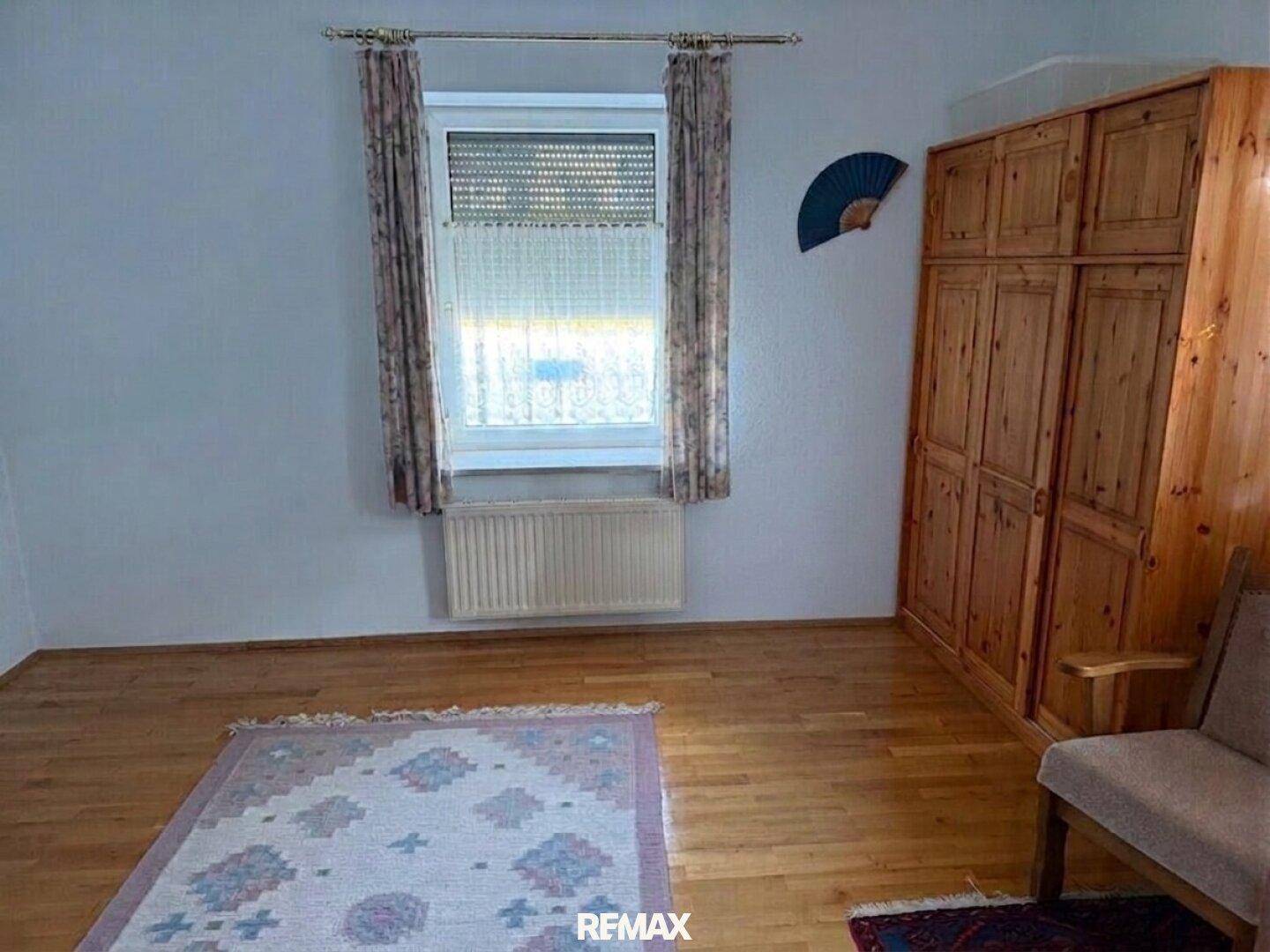 Helles Schlafzimmer mit Holzboden, großem Kleiderschrank und Fenster.
