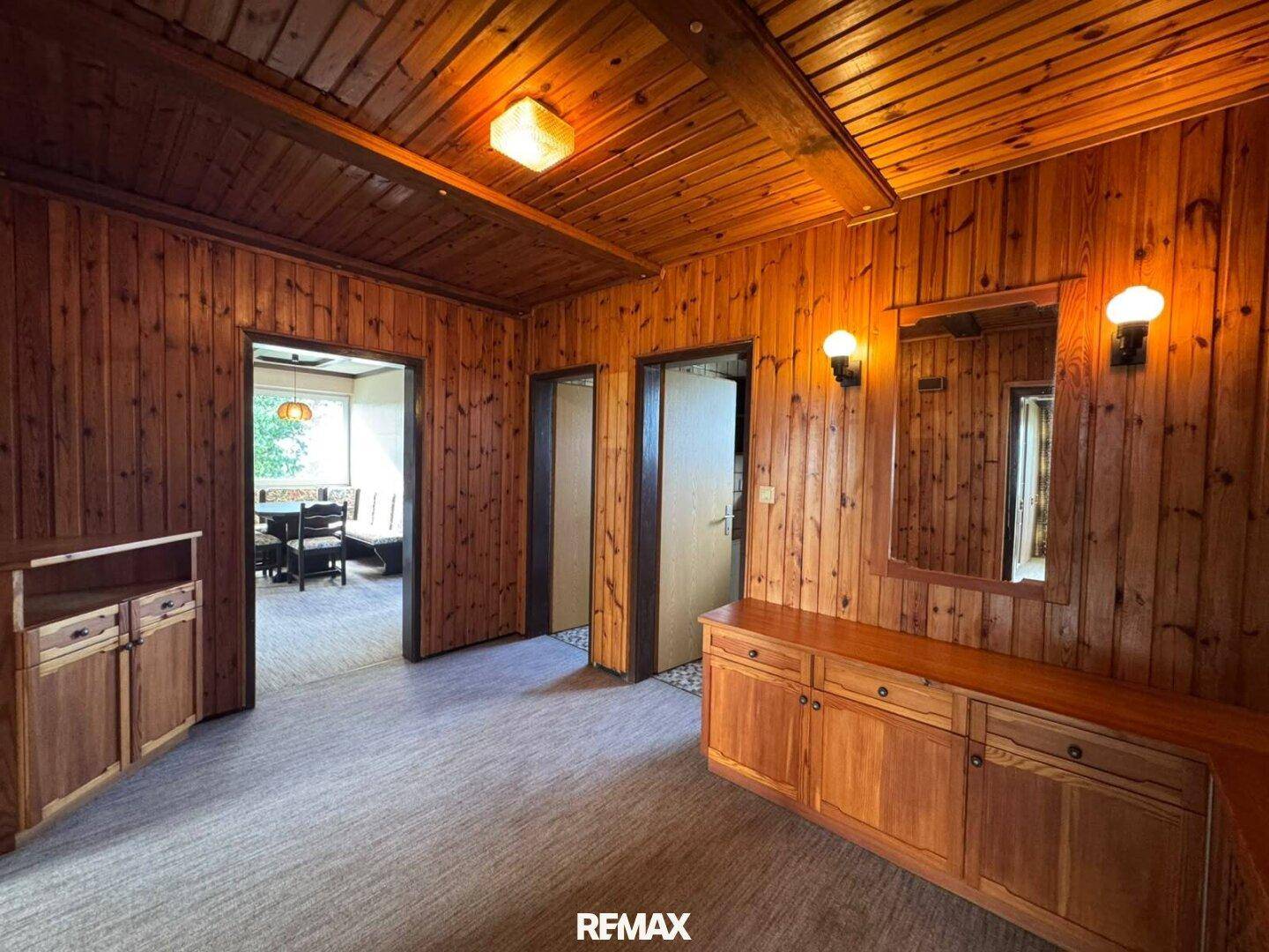 Flur mit holzvertäfelten Wänden und Decke, sowie rustikalen Holzmöbeln.