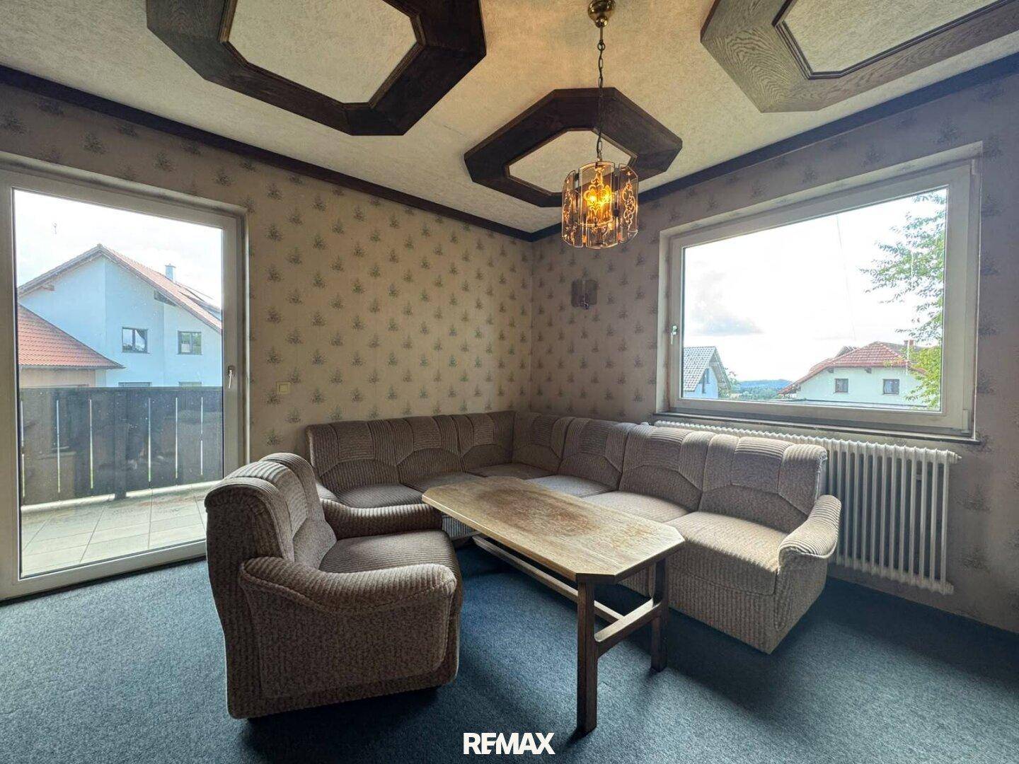 Gemütliches Wohnzimmer mit Ecksofa, Couchtisch und Zugang zum Balkon.