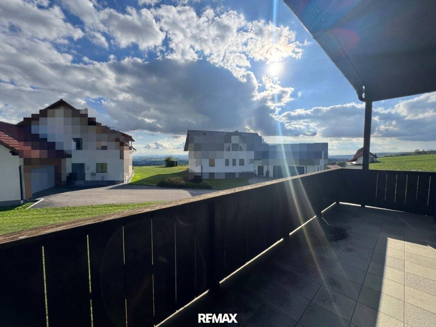 Balkon mit Fliesenboden und Holzgeländer, bietet weiten Blick auf die Umgebung.