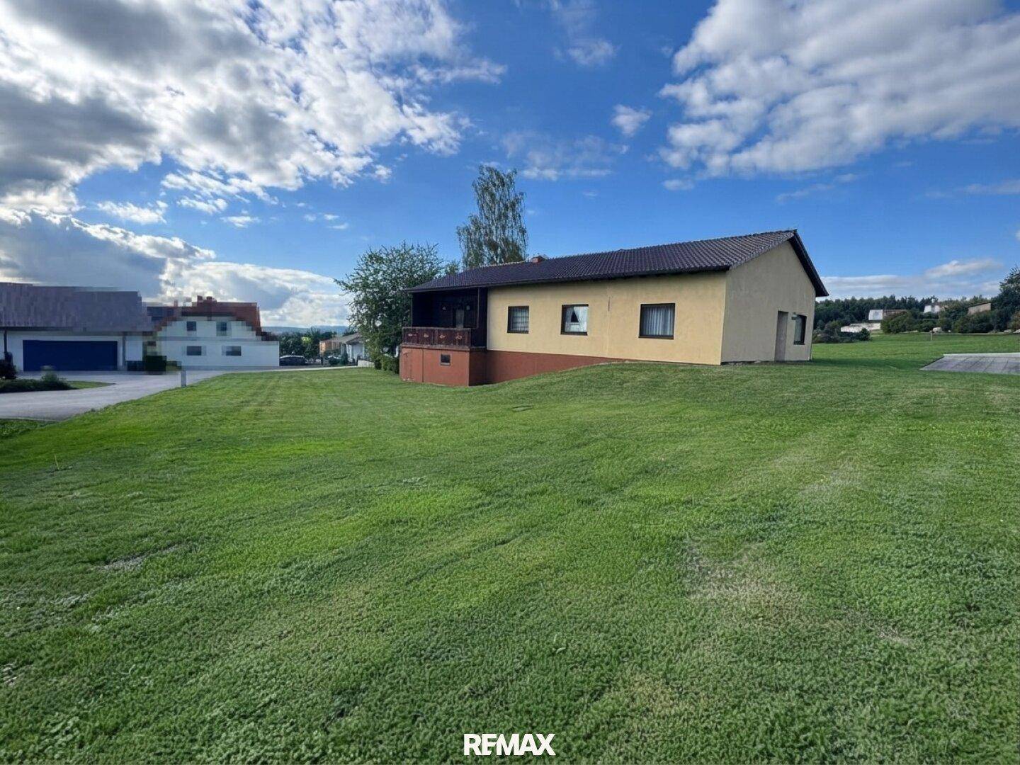 Weitläufiger Blick auf das Einfamilienhaus mit großem Rasen und ländlicher Umgebung.