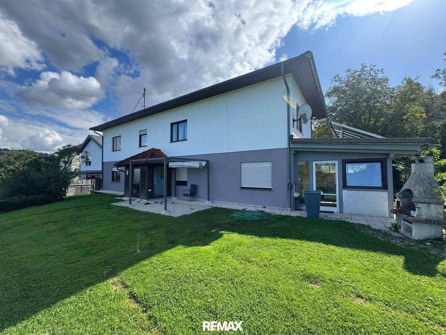 Rückansicht des Hauses mit weitläufiger Rasenfläche und einem überdachten Außenbereich.