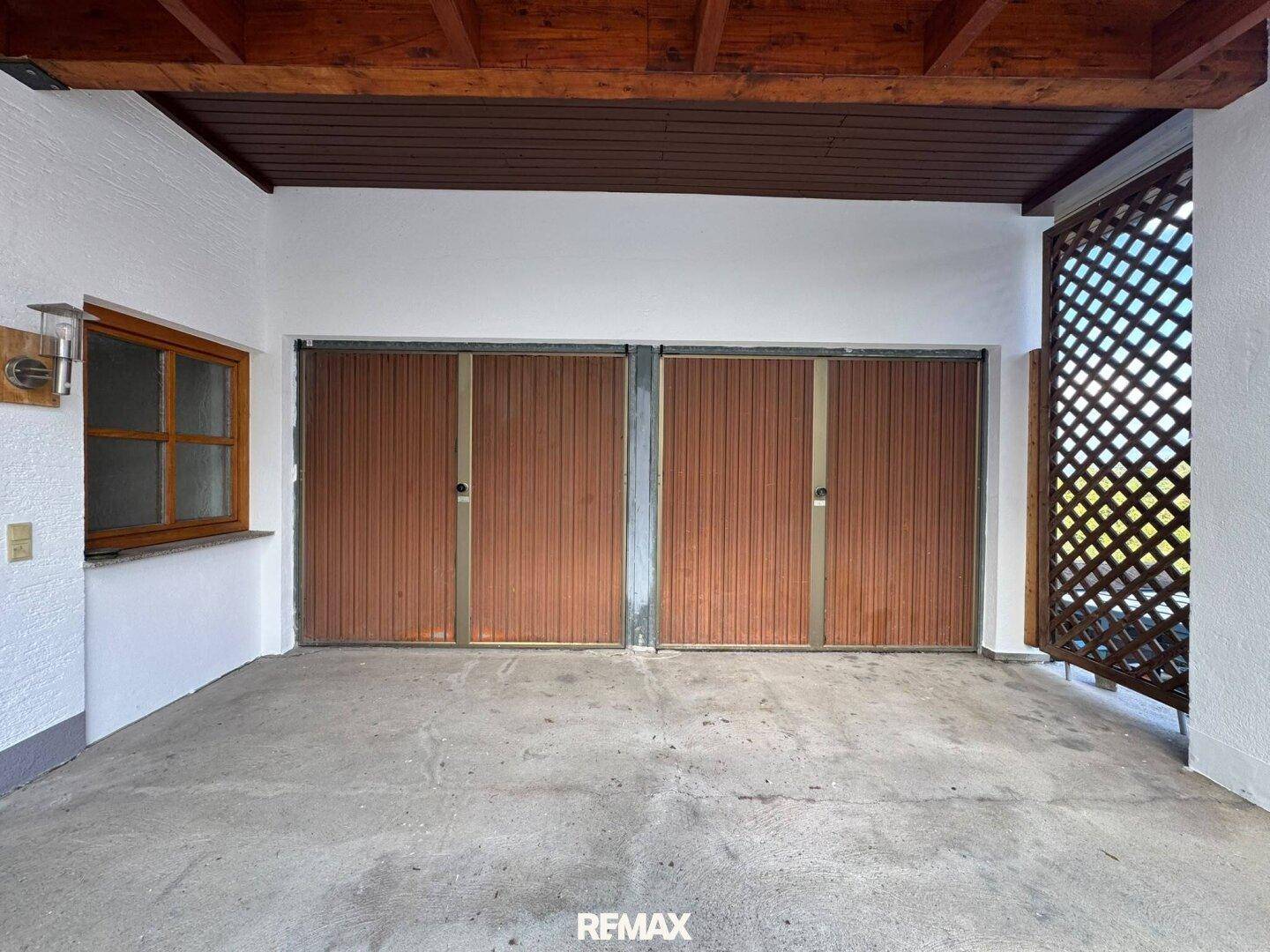Geräumige Garage mit zwei Holztoren und ausreichend Platz für Fahrzeuge oder Lagerung.