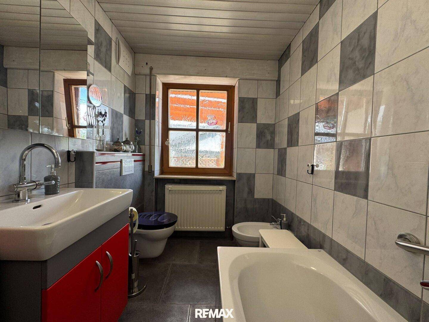 Modern gefliestes Badezimmer mit Badewanne, Bidet, WC und Einzelwaschbecken.