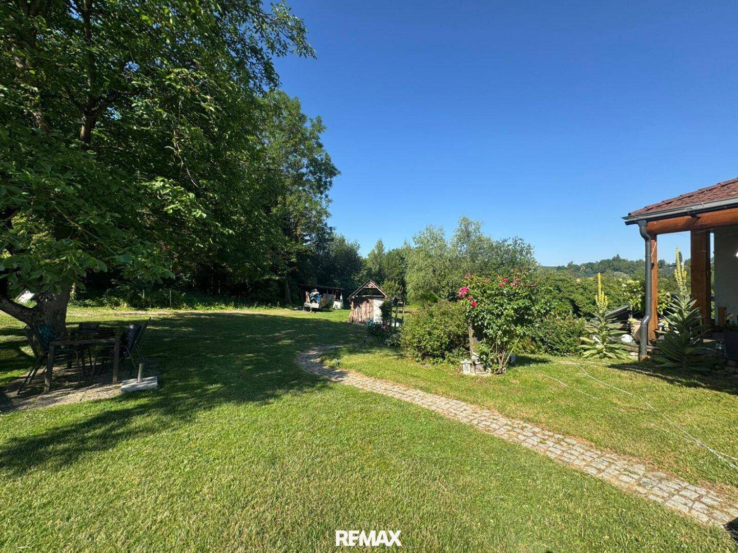 Weitläufiger, gepflegter Garten mit Rasenfläche, altem Baumbestand und Sitzgelegenheiten.