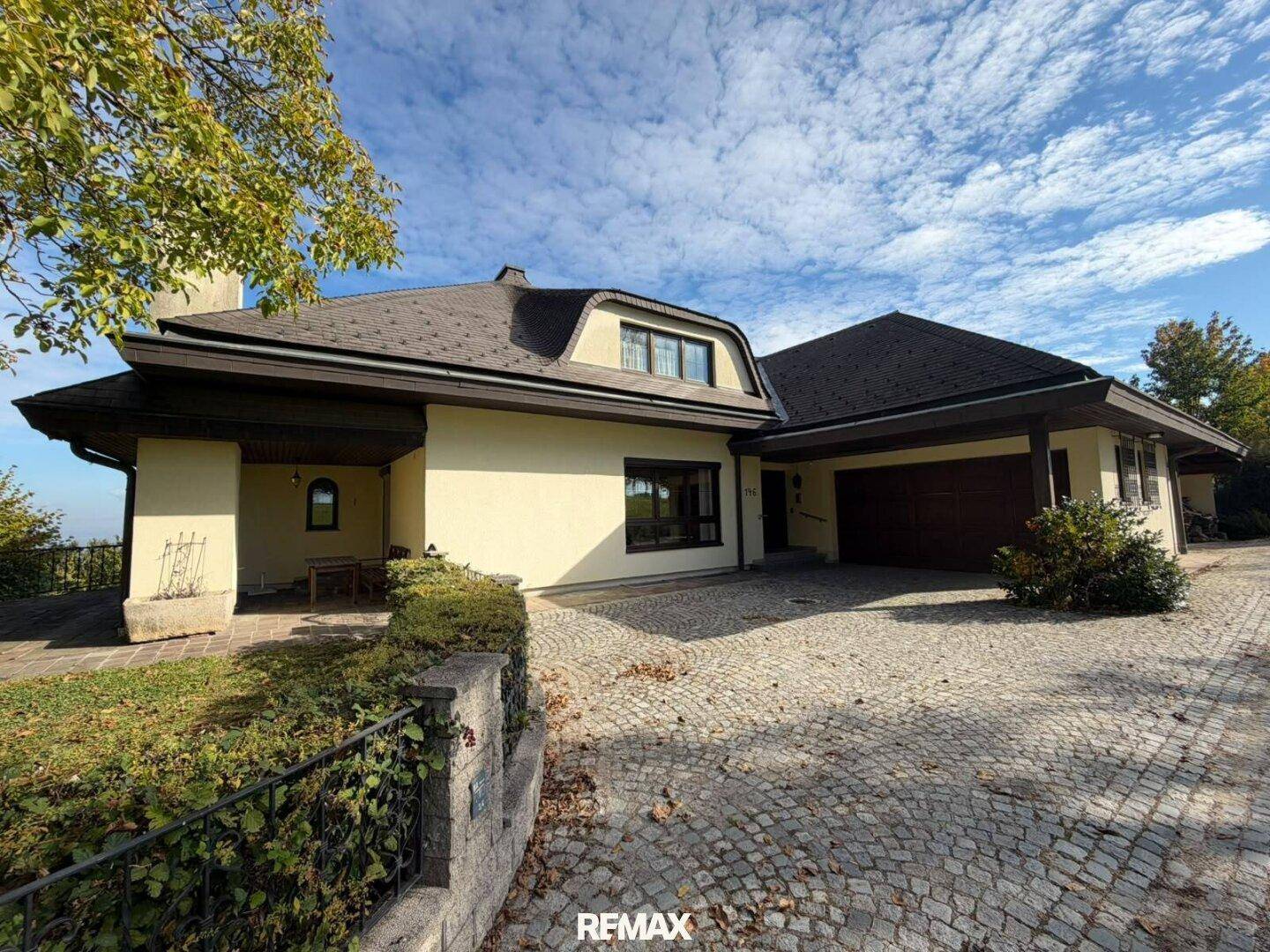 Hausansicht mit gepflasterter Auffahrt, Garage und einem kleinen überdachten Eingangsbereich.