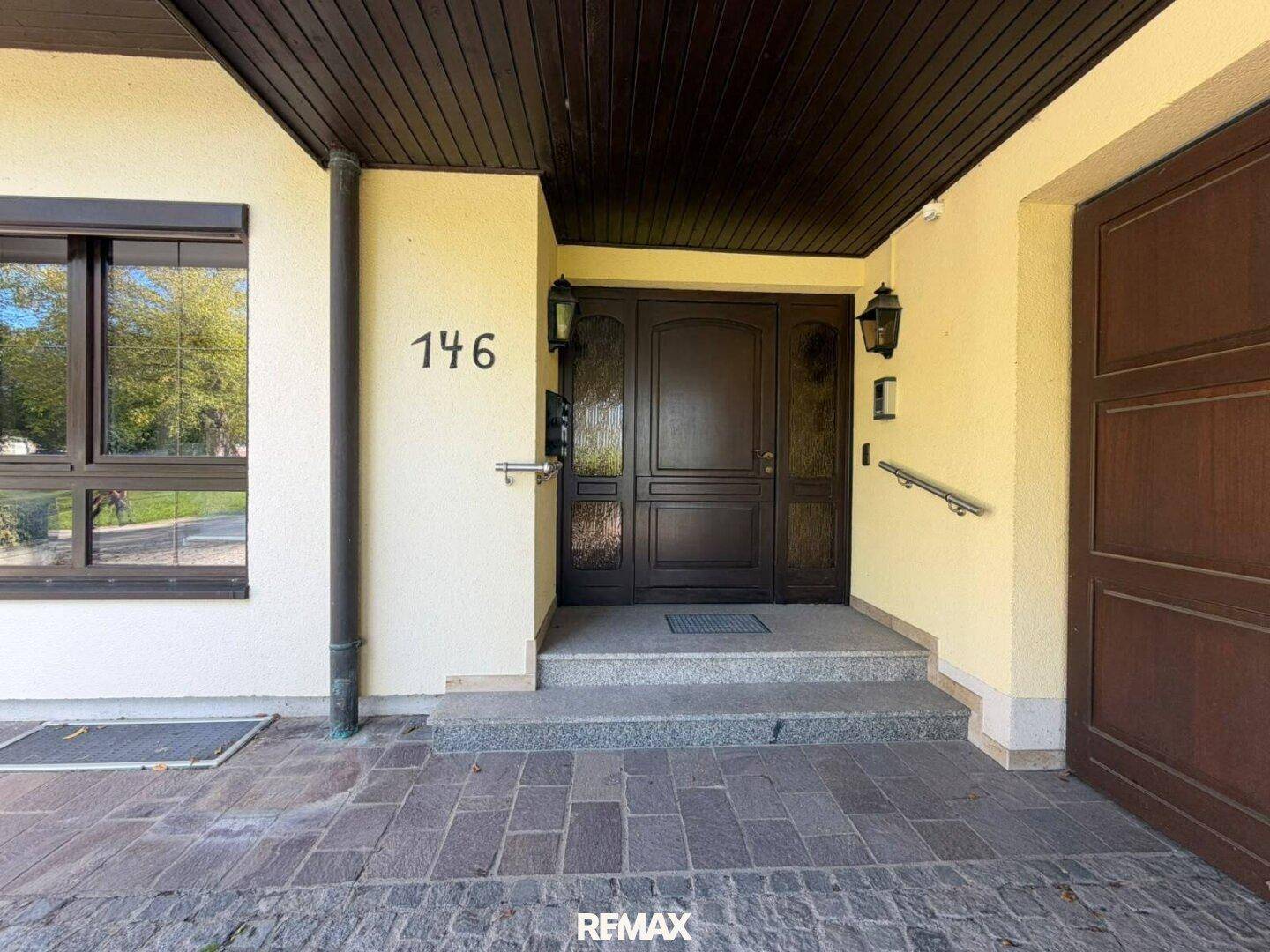Haupteingang des Hauses mit massiver Holztür, Hausnummer und traditionellen Außenleuchten.