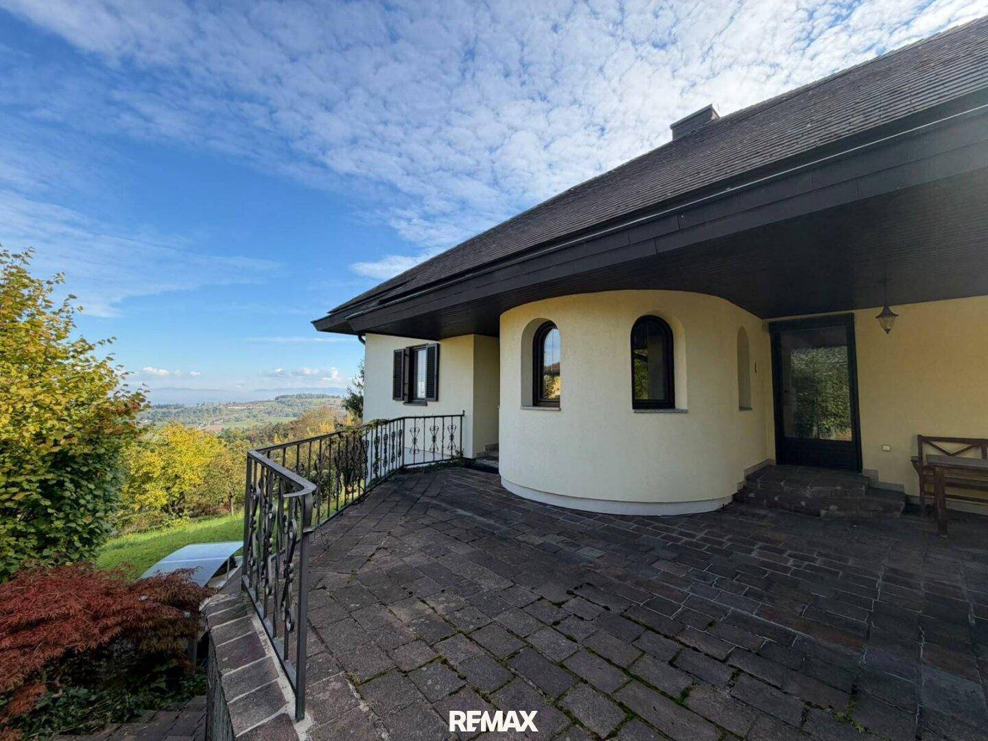 Große gepflasterte Terrasse mit schmiedeeisernem Geländer und weitem Blick ins Grüne.
