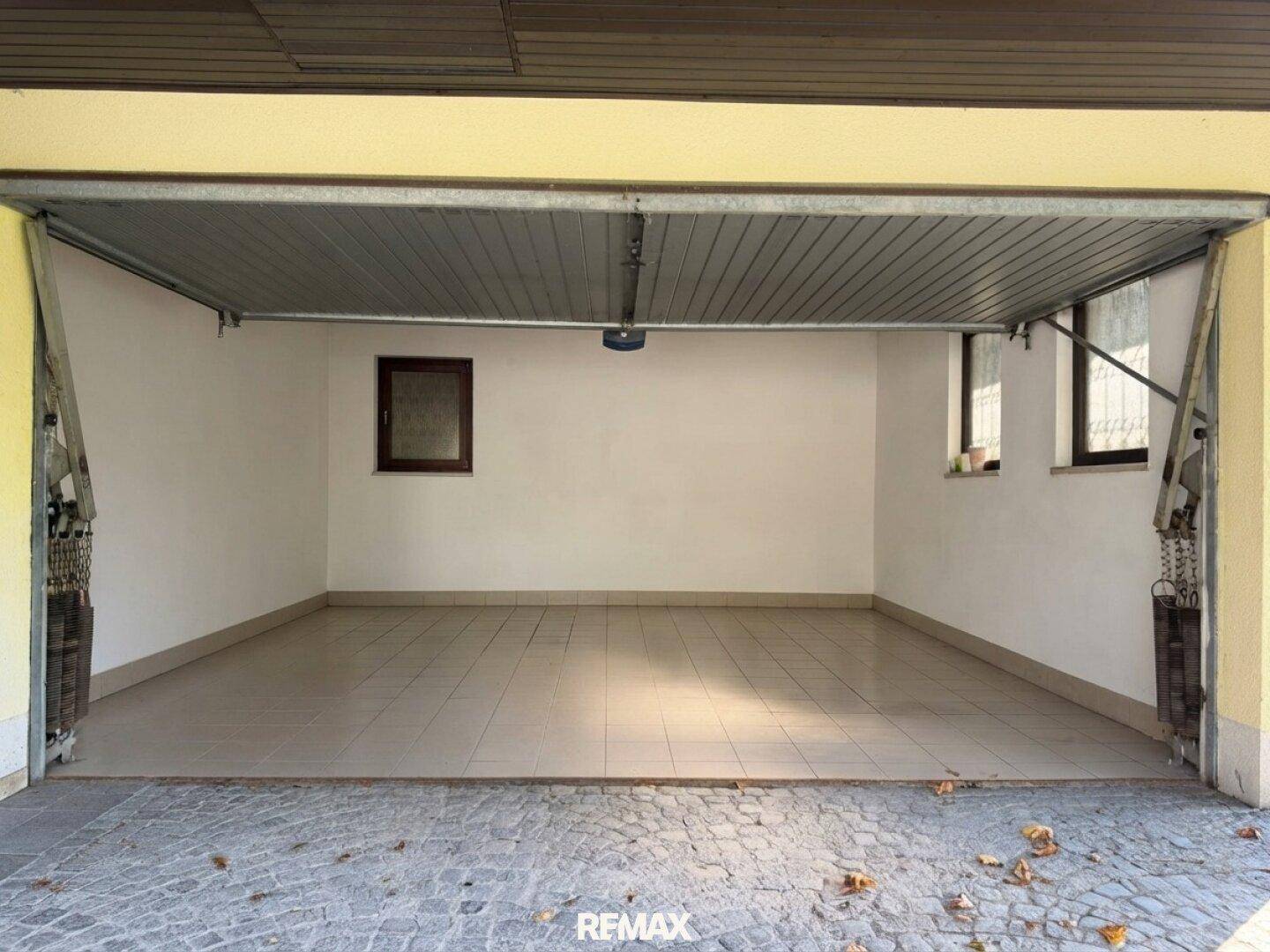 Geräumige Garage mit Fliesenboden und Fenstern, bietet Platz für ein Fahrzeug.