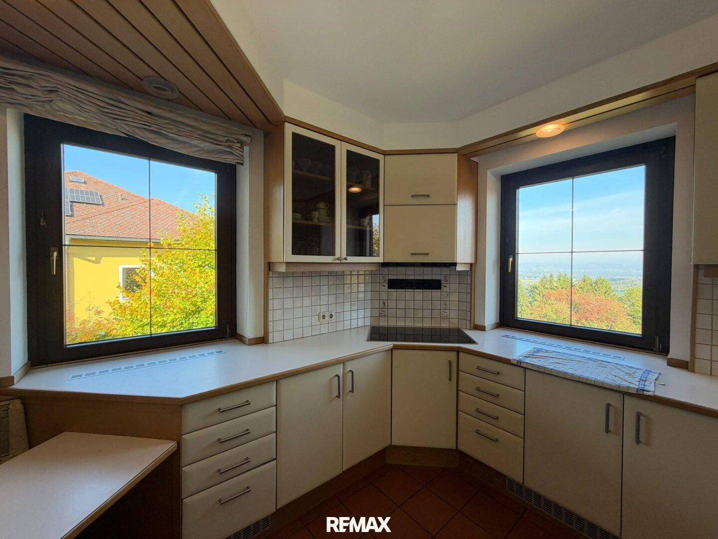 Helle Küche mit Einbauküche, Kochfeld und weitem Ausblick durch die Fenster.