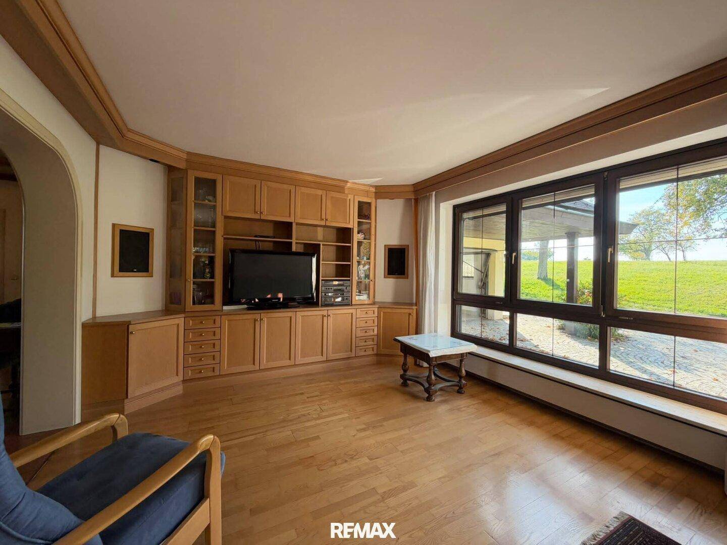 Geräumiges Wohnzimmer mit Holzfußboden, Einbauschränken und großen Fenstern mit Ausblick.