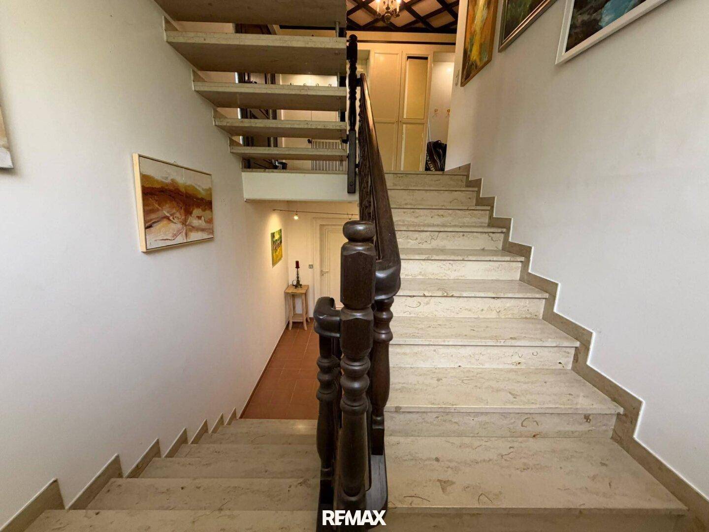 Elegante Steintreppe mit Holzgeländer führt in die oberen Etagen des Hauses.