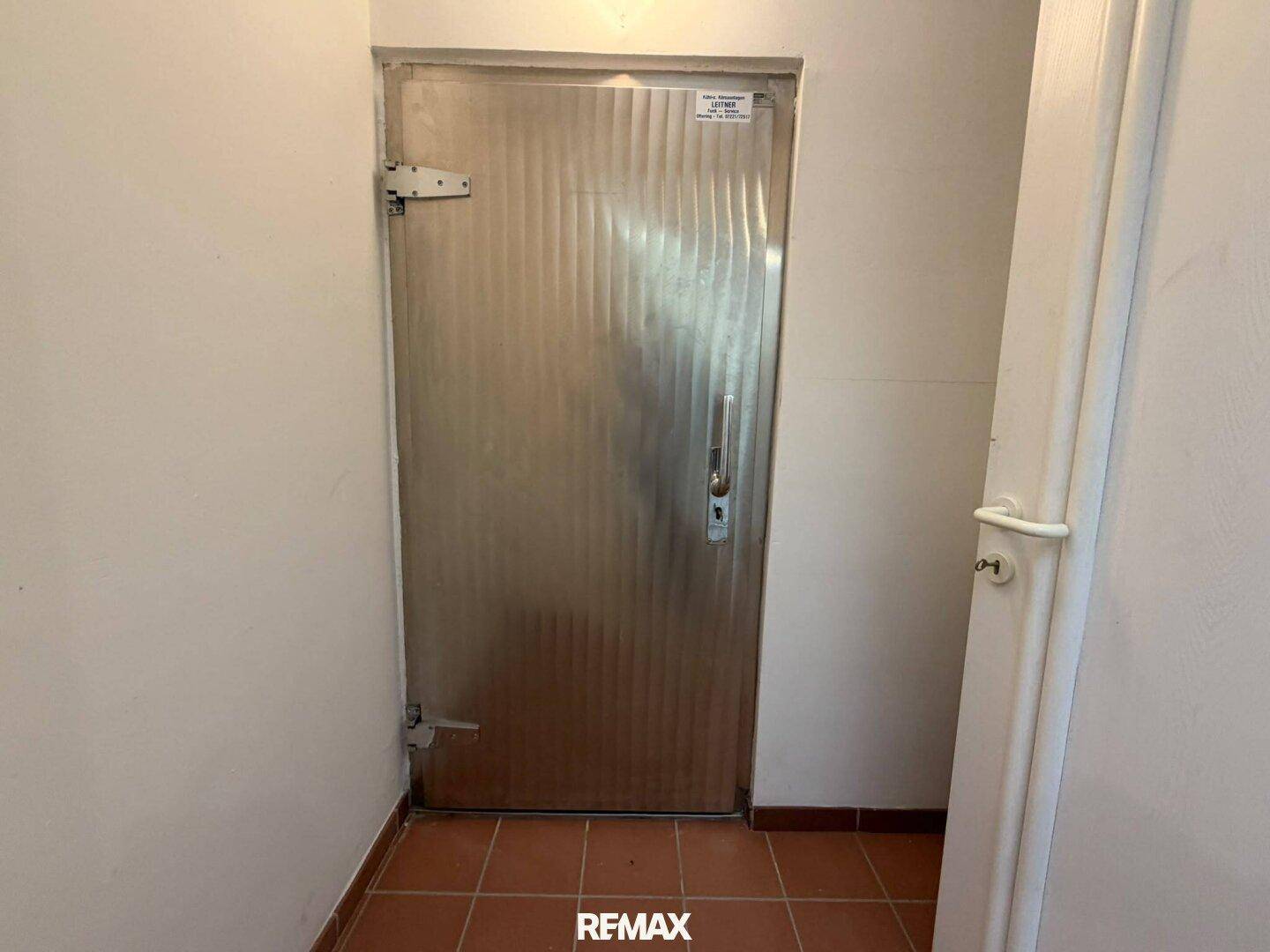 Robuste Metalltür in einem Flur mit Terrakotta-Fliesenboden, ideal für einen Abstellraum.