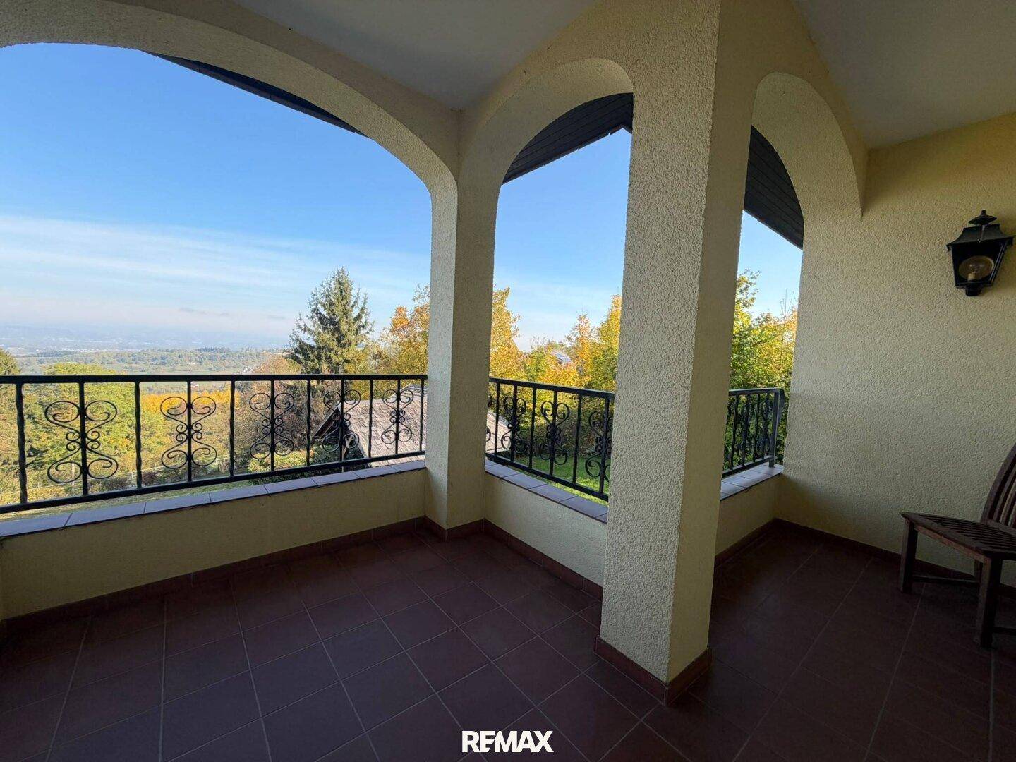 Überdachte Loggia mit weitem Blick ins Grüne und schmiedeeisernem Geländer, ideal zum Entspannen.