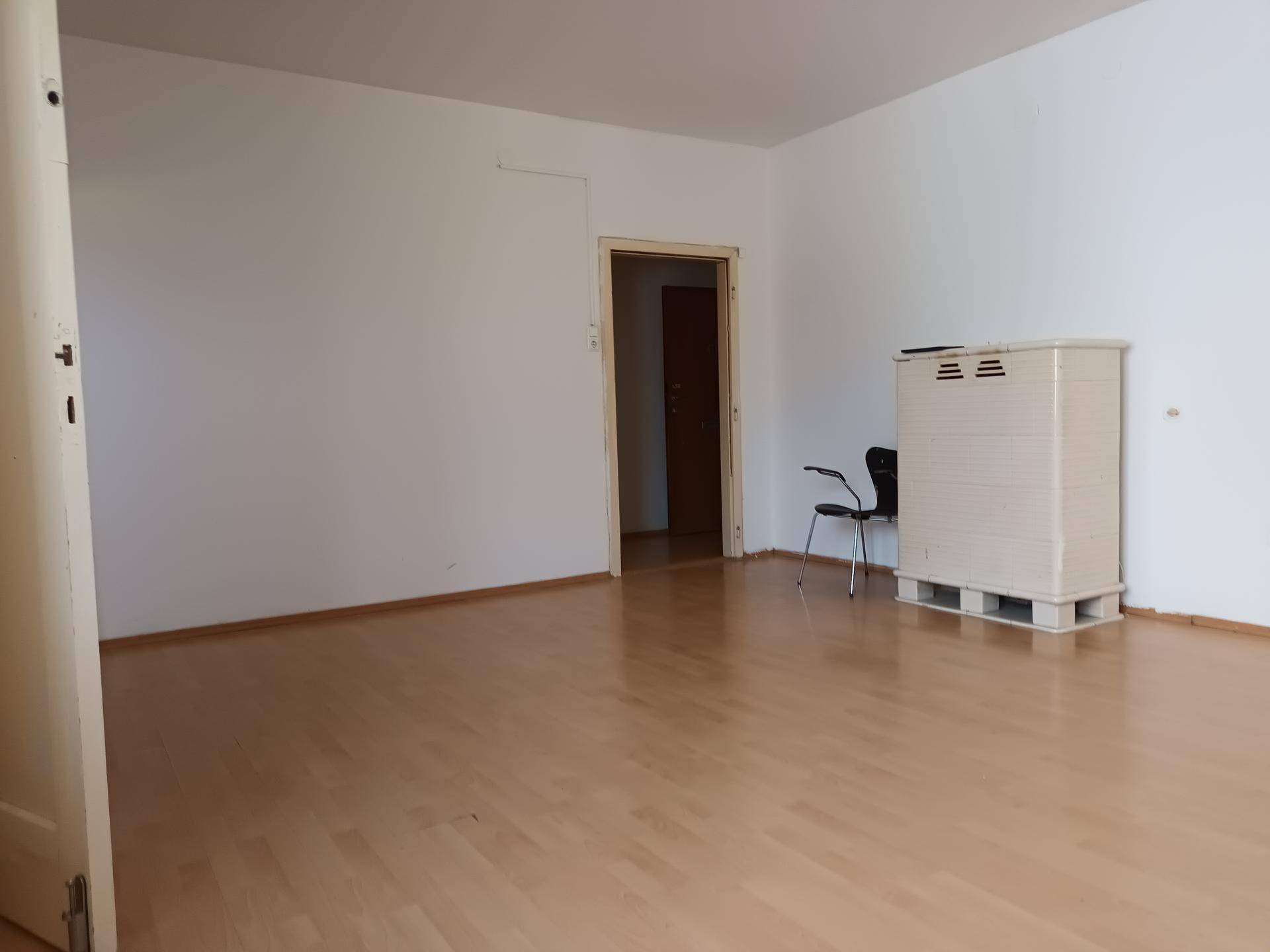 Heller, leerer Raum mit Laminatboden und einer Tür, ideal für verschiedene Wohnkonzepte.