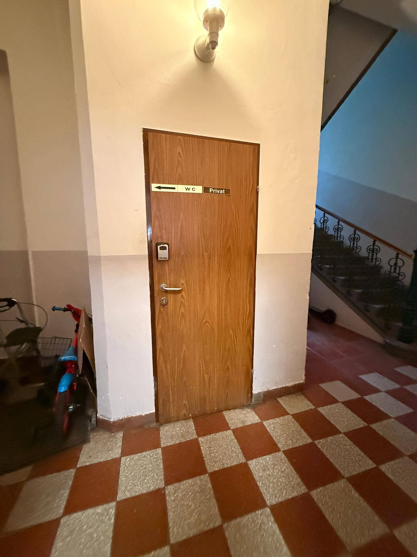 Eine Holztür mit "WC Privat"-Schild neben einer Treppe, die zu einem privaten Toilettenbereich führt.