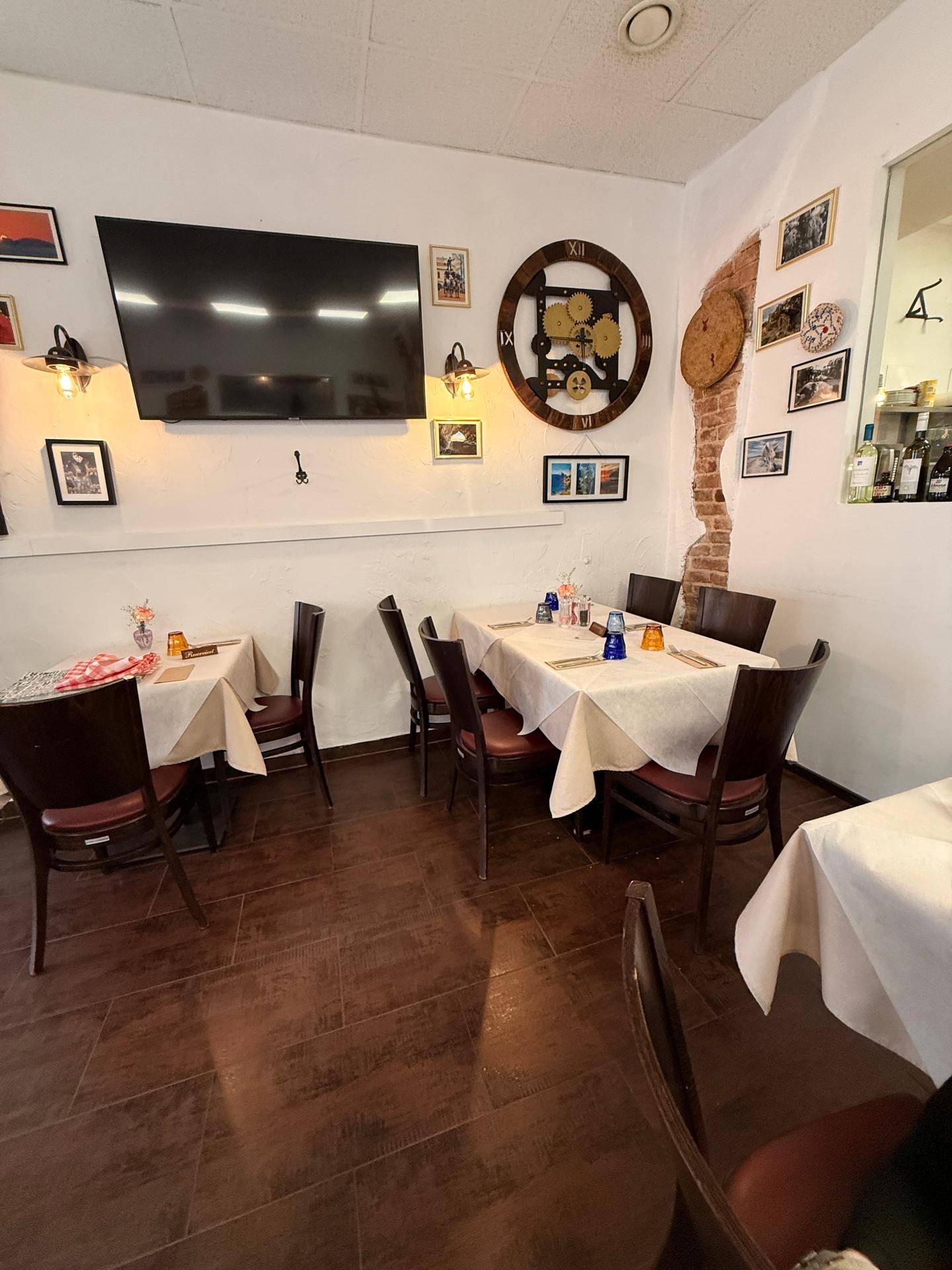 Geräumiger Restaurant-Essbereich mit mehreren gedeckten Tischen, dunklen Stühlen und Wanddekorationen.