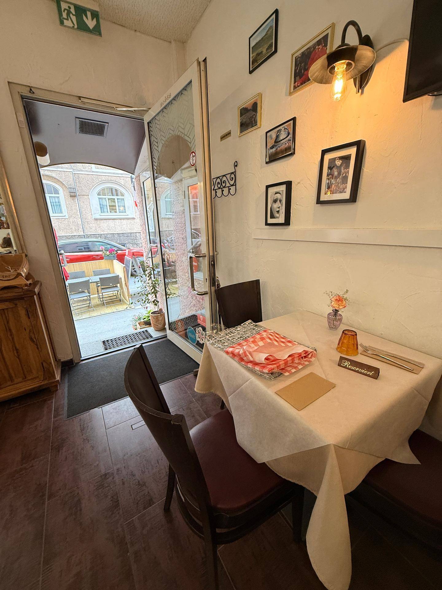 Gastraum eines Restaurants mit gedecktem Tisch und Blick auf den Eingangsbereich und die Außenterrasse.
