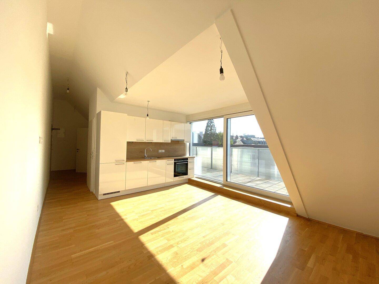 Helle, offene Küche mit weißen Hochglanzschränken, Holzboden und Zugang zur Terrasse.