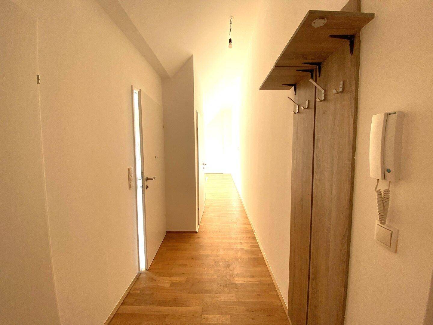 Heller Flur mit Holzboden und einer modernen Garderobe aus hellem Holz.