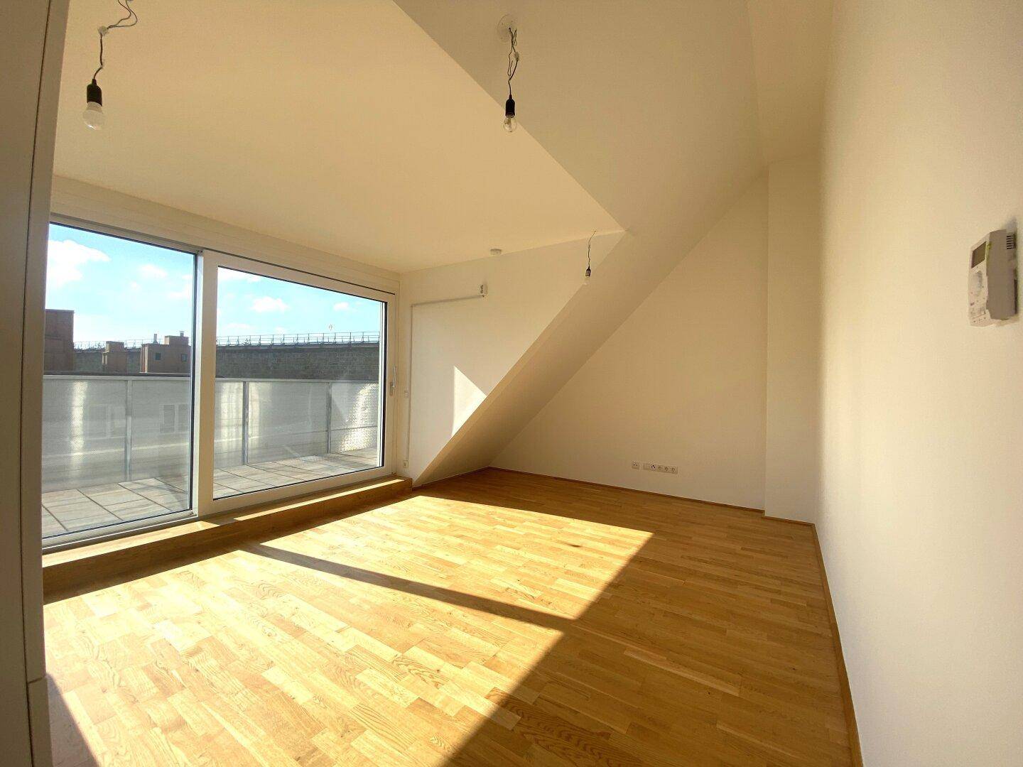 Lichtdurchfluteter Wohnbereich mit Holzboden, großen Fenstern und direktem Zugang zur sonnigen Terrasse.