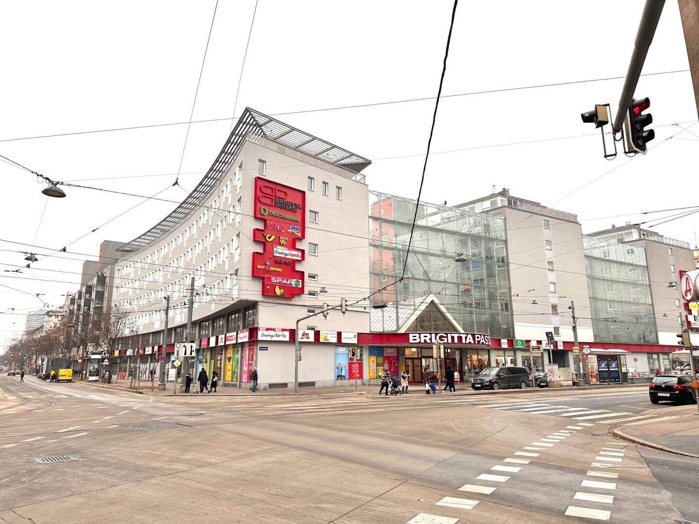 Großer Gebäudekomplex der Brigitta Passage mit Geschäften und Wohnungen an einer belebten Kreuzung.