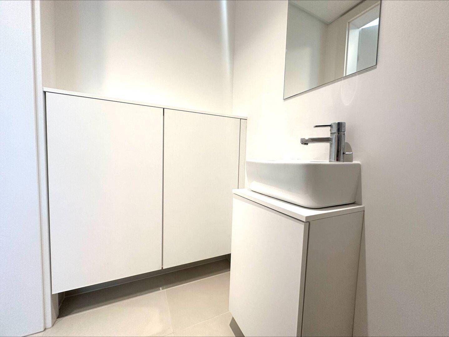 Modernes Gäste-WC mit elegantem Aufsatzwaschbecken und praktischem Spiegelschrank, in hellen Tönen.