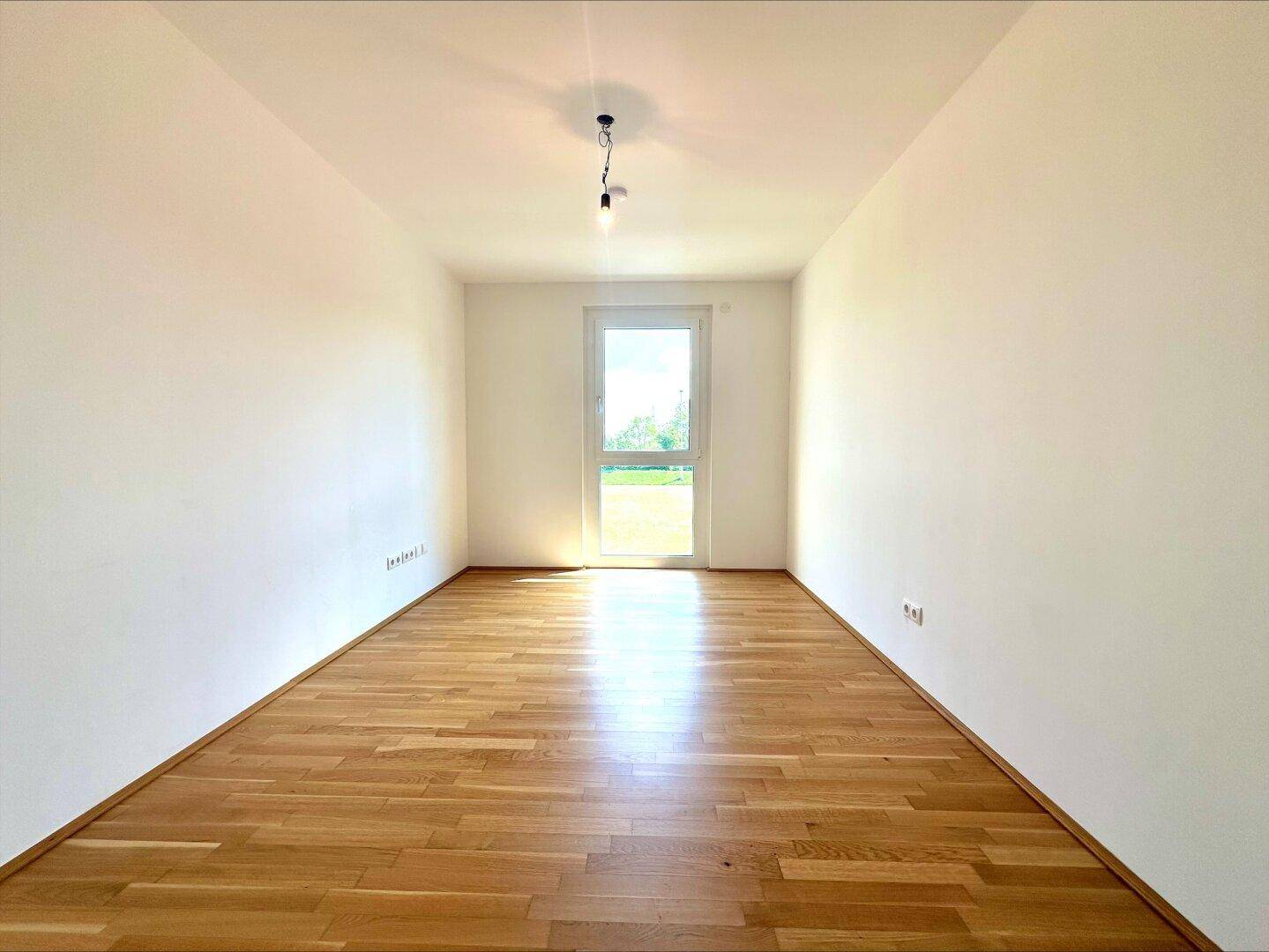 Helles Zimmer mit Parkettboden und Zugang zum Garten, ideal als Schlaf- oder Arbeitszimmer nutzbar.
