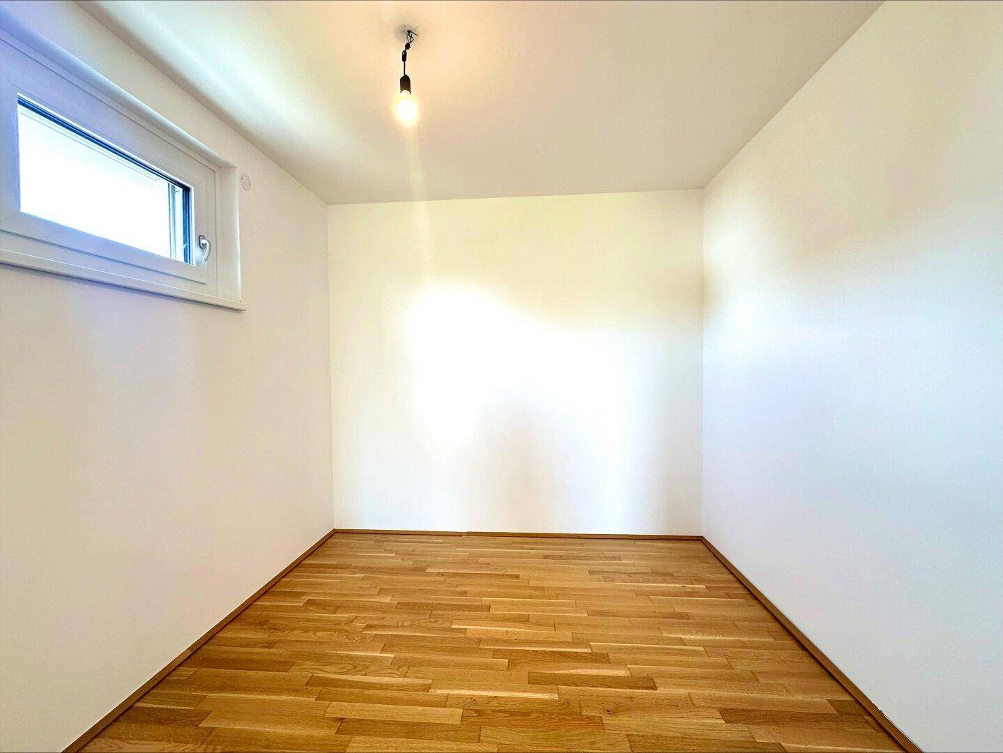 Kleineres Zimmer mit Parkettboden und Fenster, ideal als Kinderzimmer oder Gästezimmer geeignet.