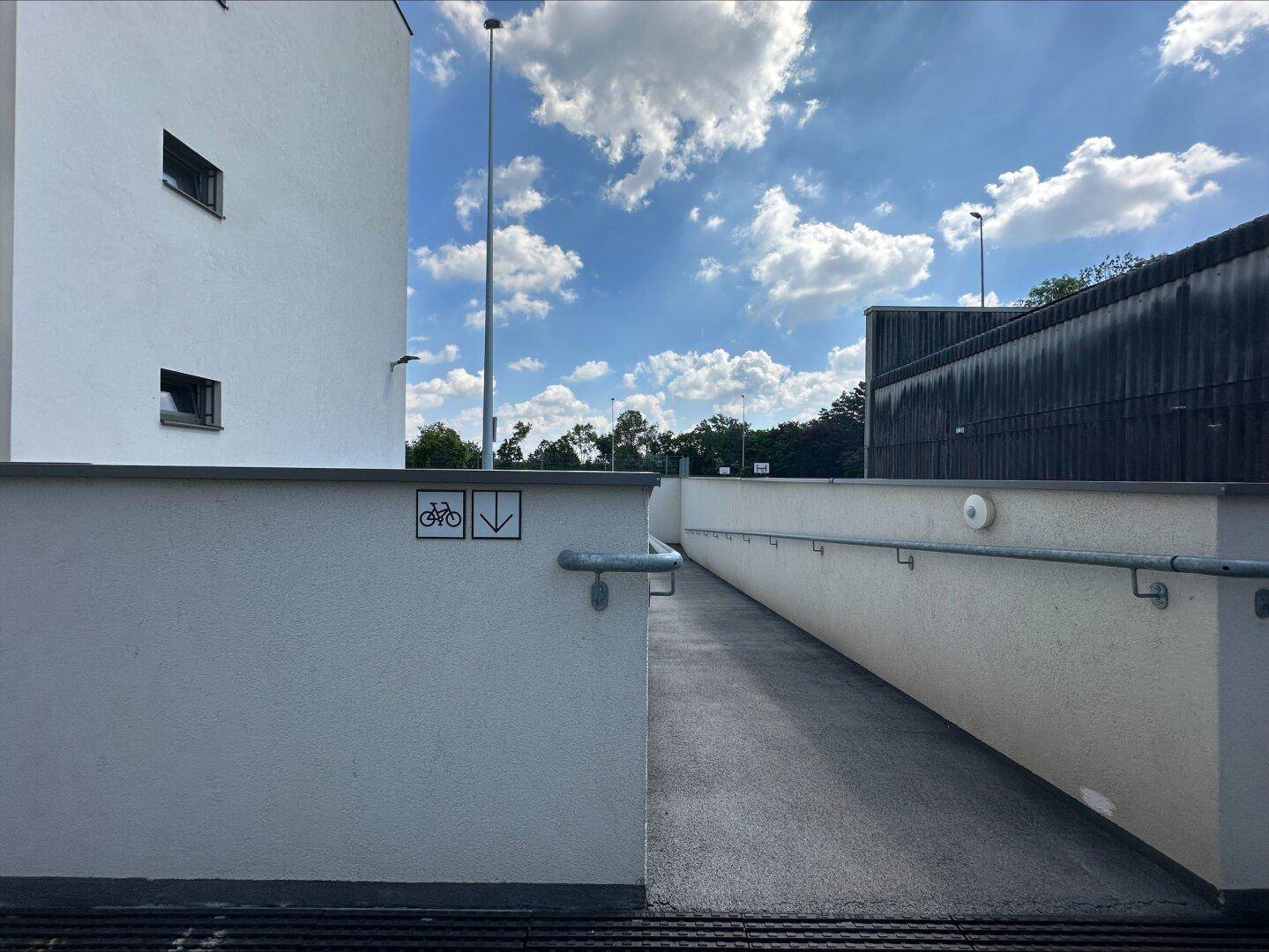 Rampe für Fahrräder und Fußgänger, die zu einem Gebäude oder einer Tiefgarage führt.