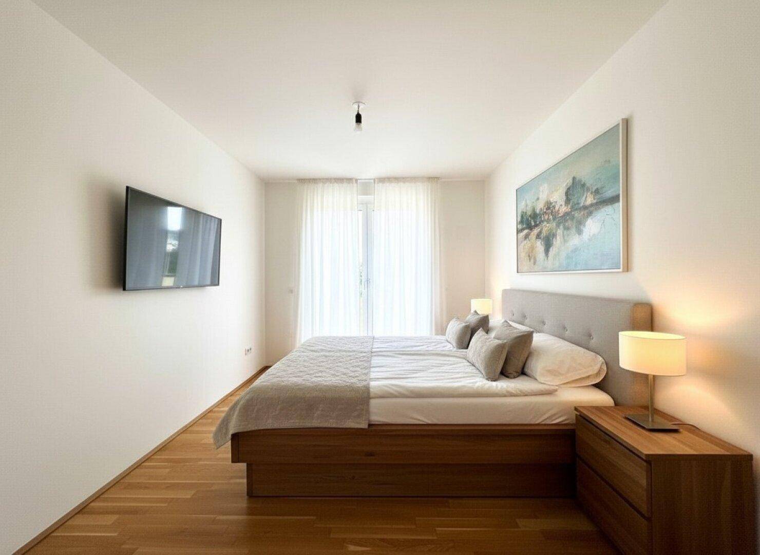 Gemütliches Schlafzimmer mit Doppelbett, Holzboden und Wandfernseher, hell und modern eingerichtet.