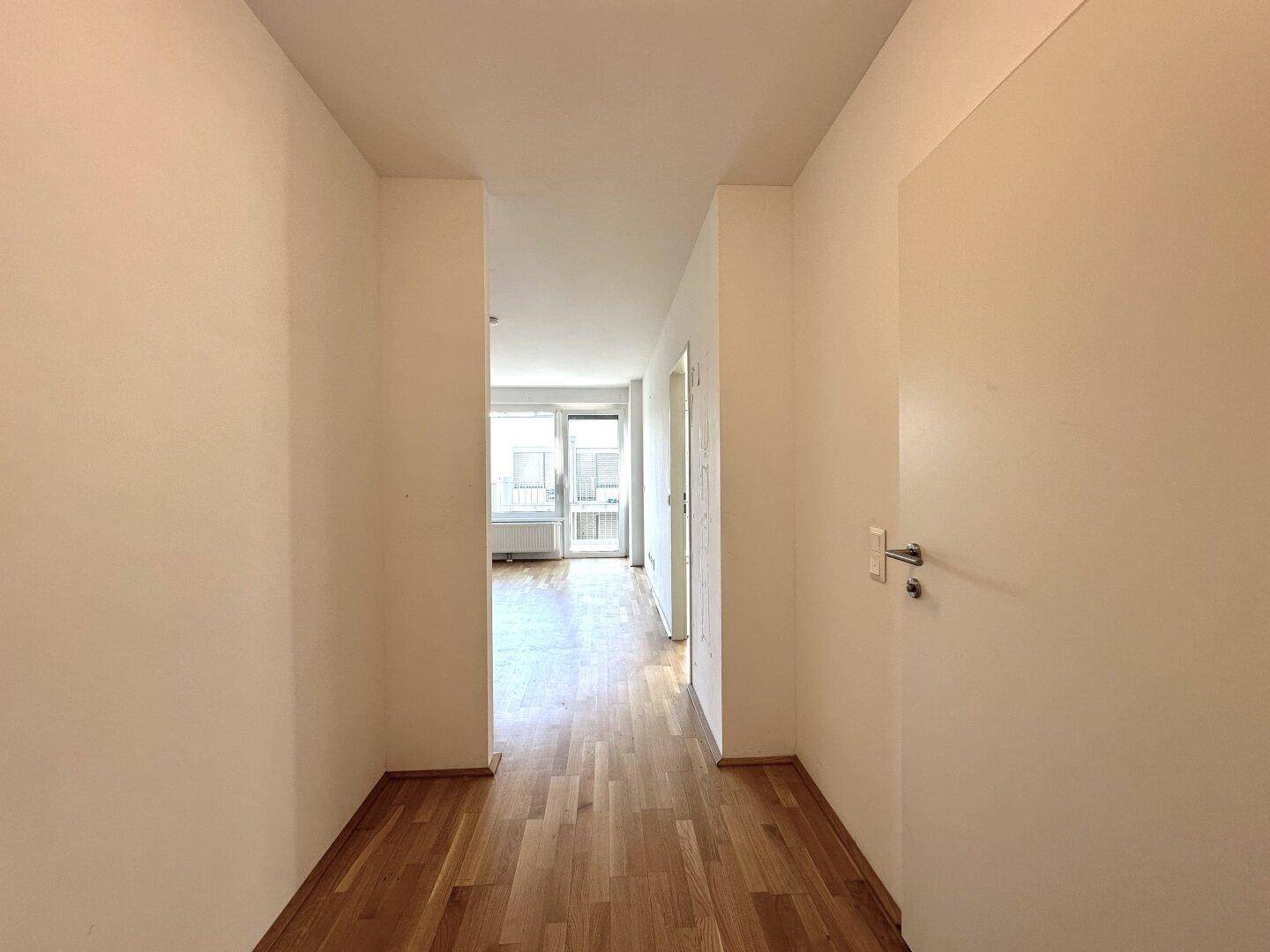 Heller Flur mit Parkettboden, der zu den verschiedenen Räumen der Wohnung führt.