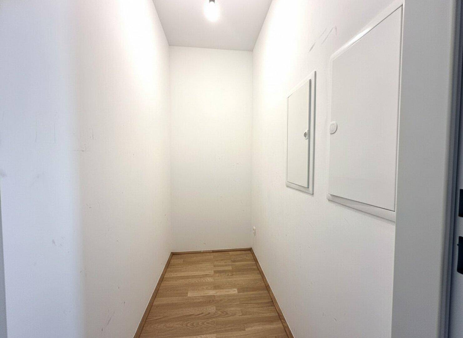 Praktischer Abstellraum mit Holzfußboden und Zugang zu den Sicherungskästen.