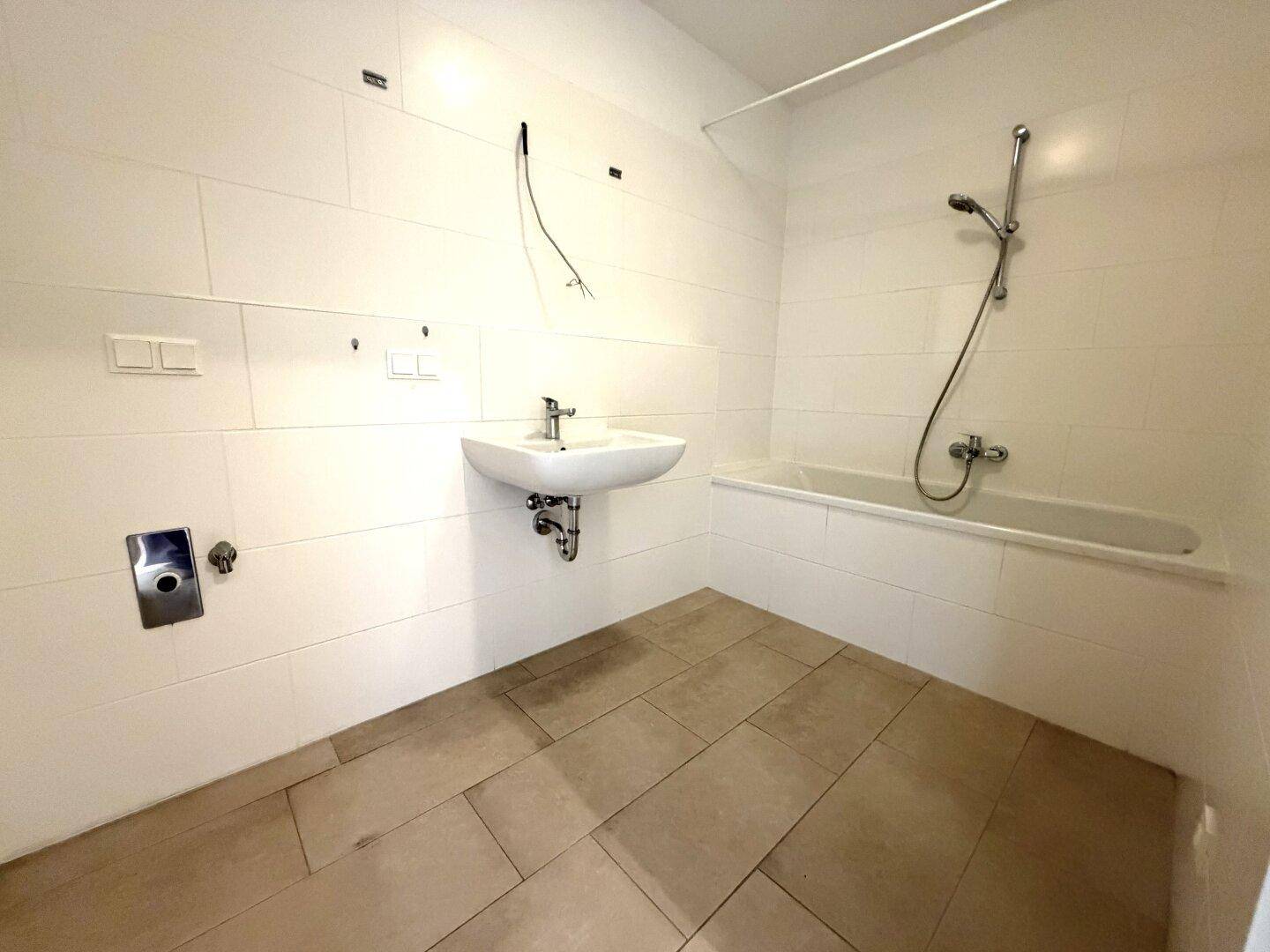 Modernes Badezimmer mit Badewanne, Waschbecken und hellen Fliesen, noch im Ausbau.
