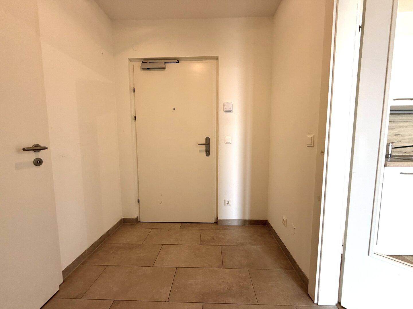Eingangsbereich mit Fliesenboden und Zugang zu den verschiedenen Räumen der Wohnung.