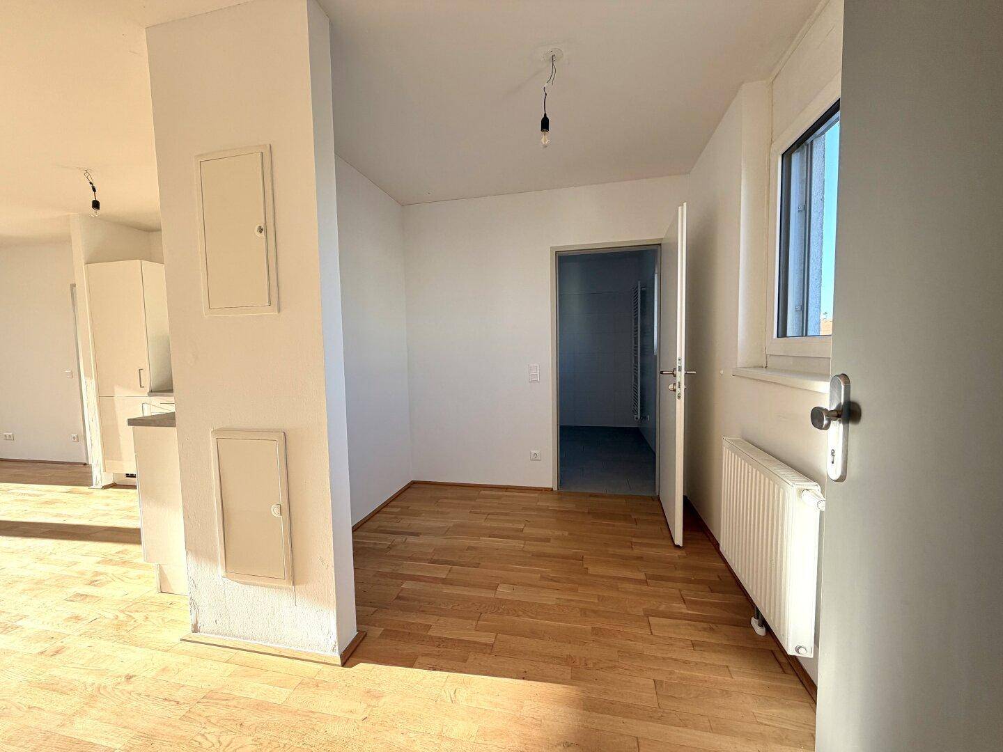 Heller Eingangsbereich mit Holzboden und Zugang zu weiteren Räumen der Wohnung.