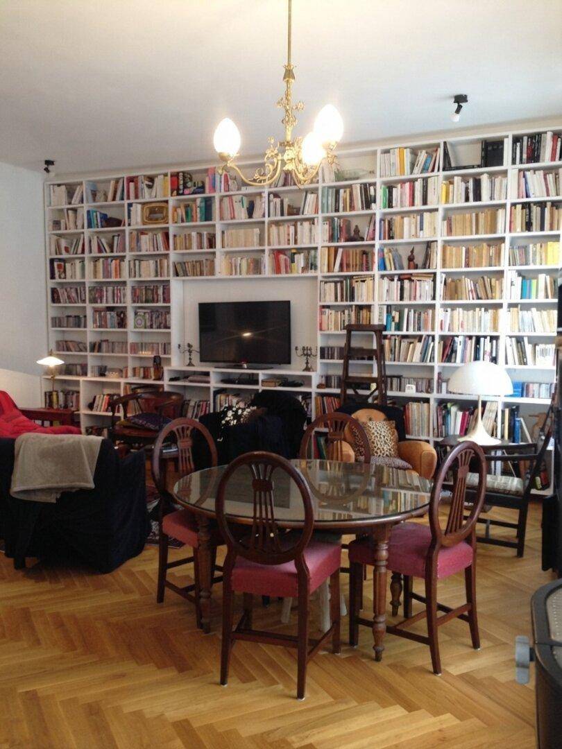 Geräumiger Wohn-Essbereich mit großer Bücherwand, Esstisch und Kronleuchter.