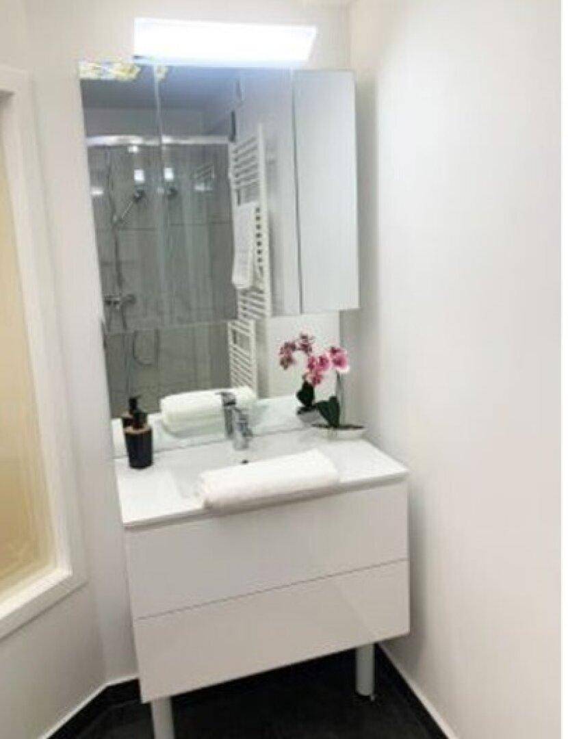 Modernes Badezimmer mit Einzelwaschbecken, Spiegelschrank und beheiztem Handtuchhalter.