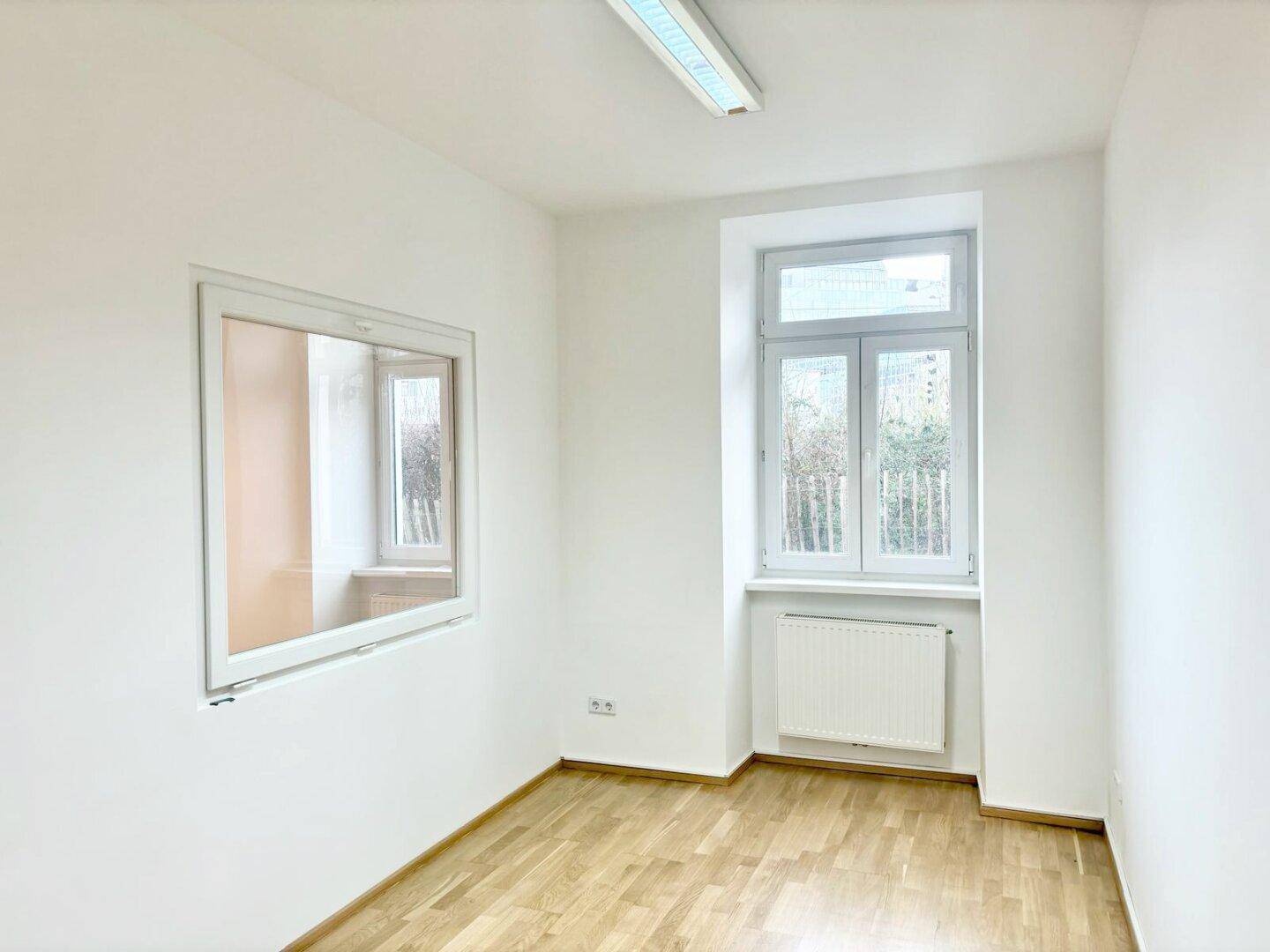 Heller Raum mit Holzparkettboden, einem Außenfenster und einem internen Fenster für mehr Licht.